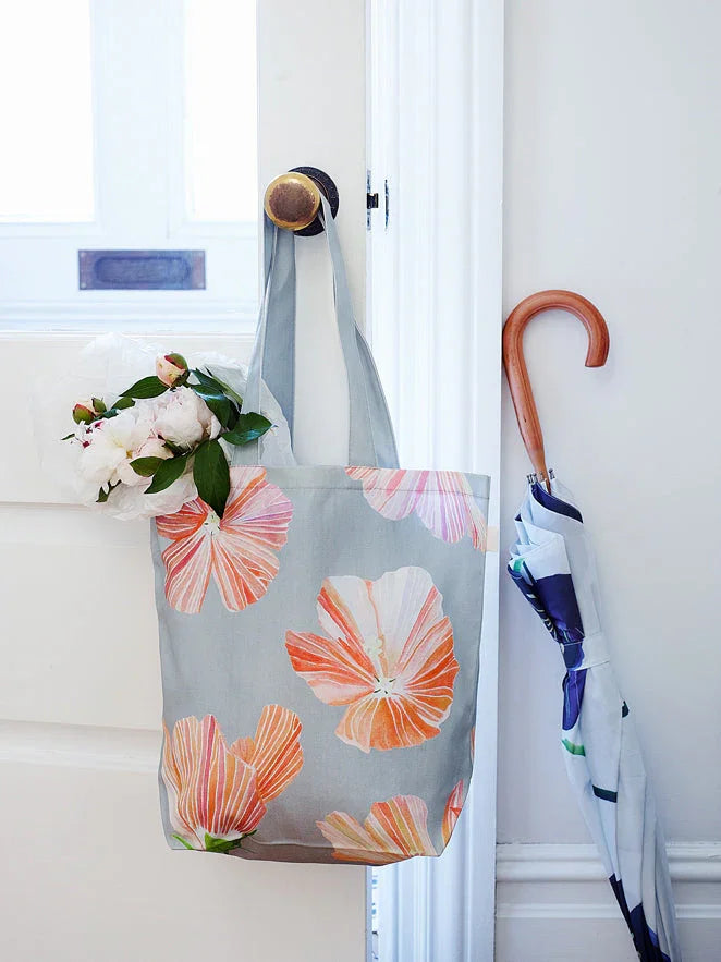 Floral hibiscus tote bag with pink and orange flowers hanging on white door knob with white peonies inside