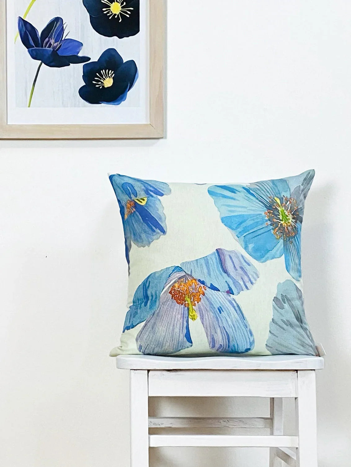Decorative pillow with blue Himalayan poppies print on white chair against white wall