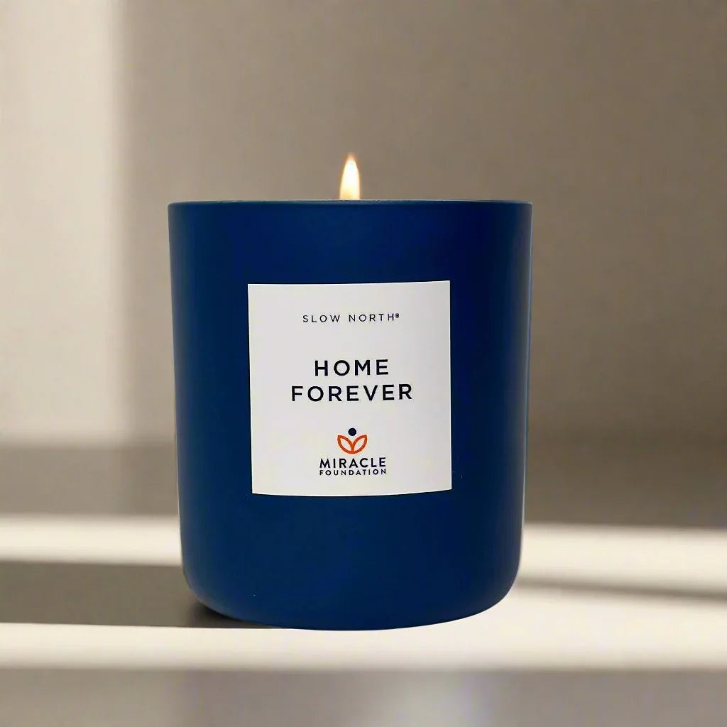 Blue Home Forever candle by Slow North, lit on a smooth surface, boutique gift shop style