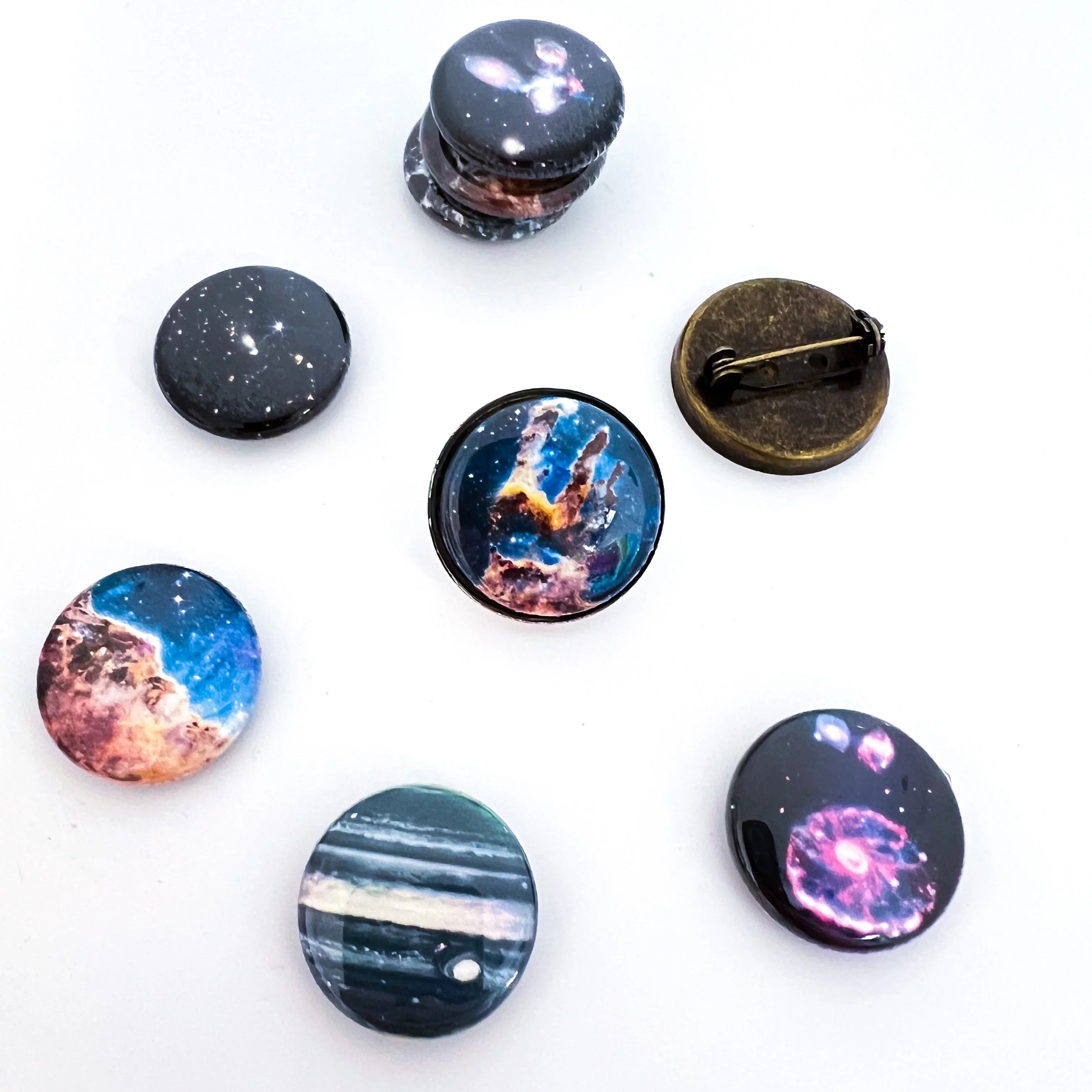 Set of round pins with space galaxy designs including nebula, planets, and stars on white background
