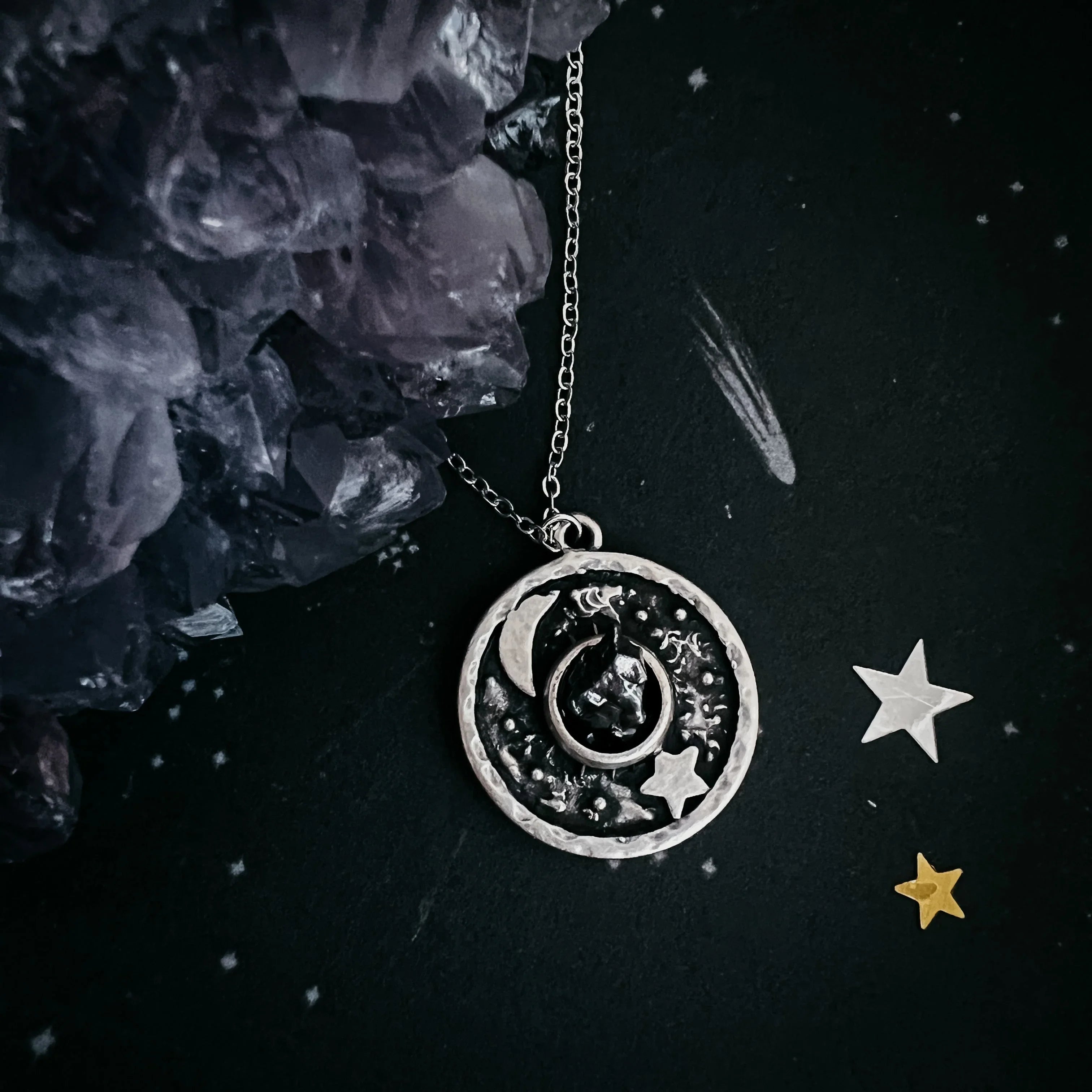 Astronomy-themed silver pendant necklace with crescent moon, star, and celestial design on black background