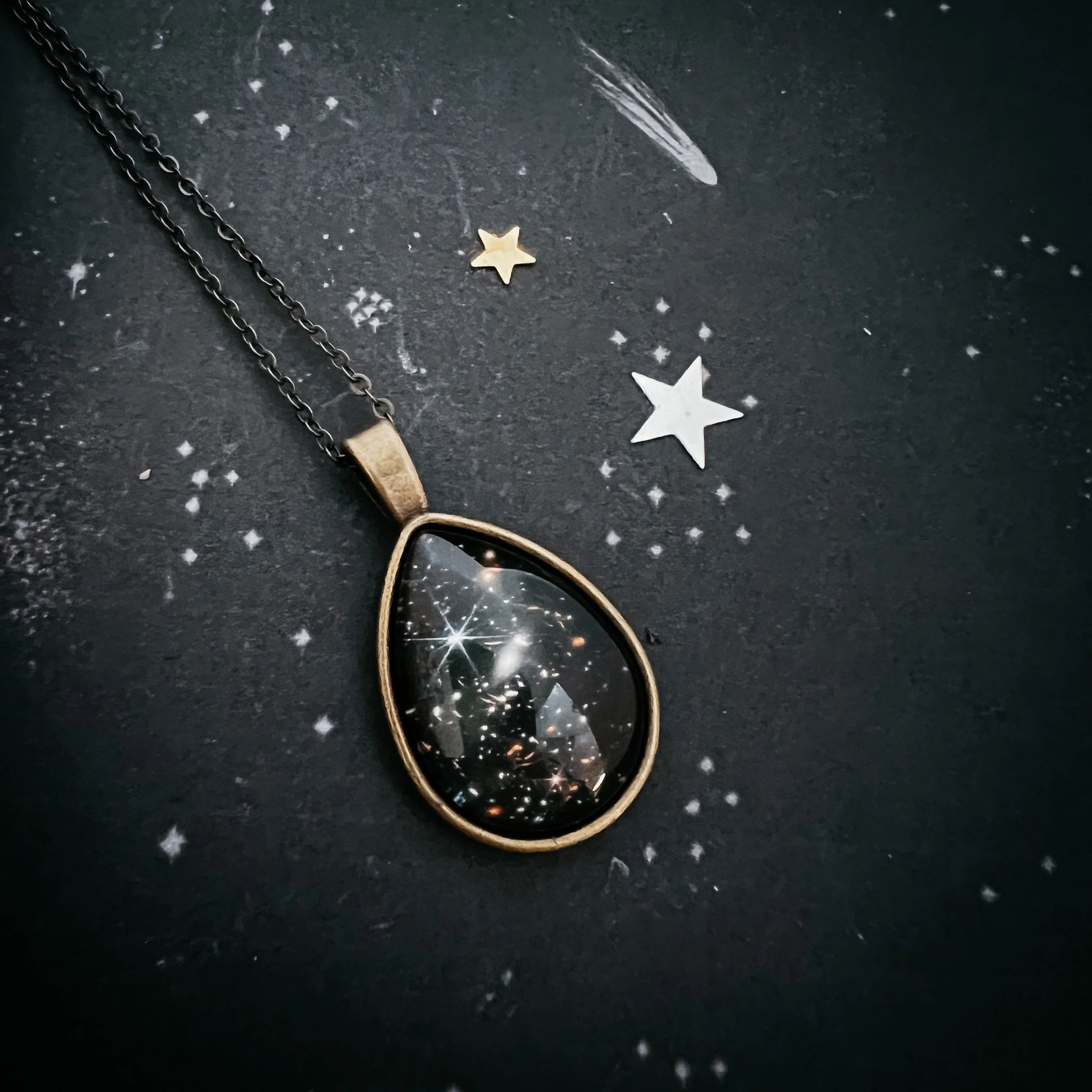 Cosmic teardrop pendant necklace on starry black background, Qu!rk Boutique artist-designed jewelry