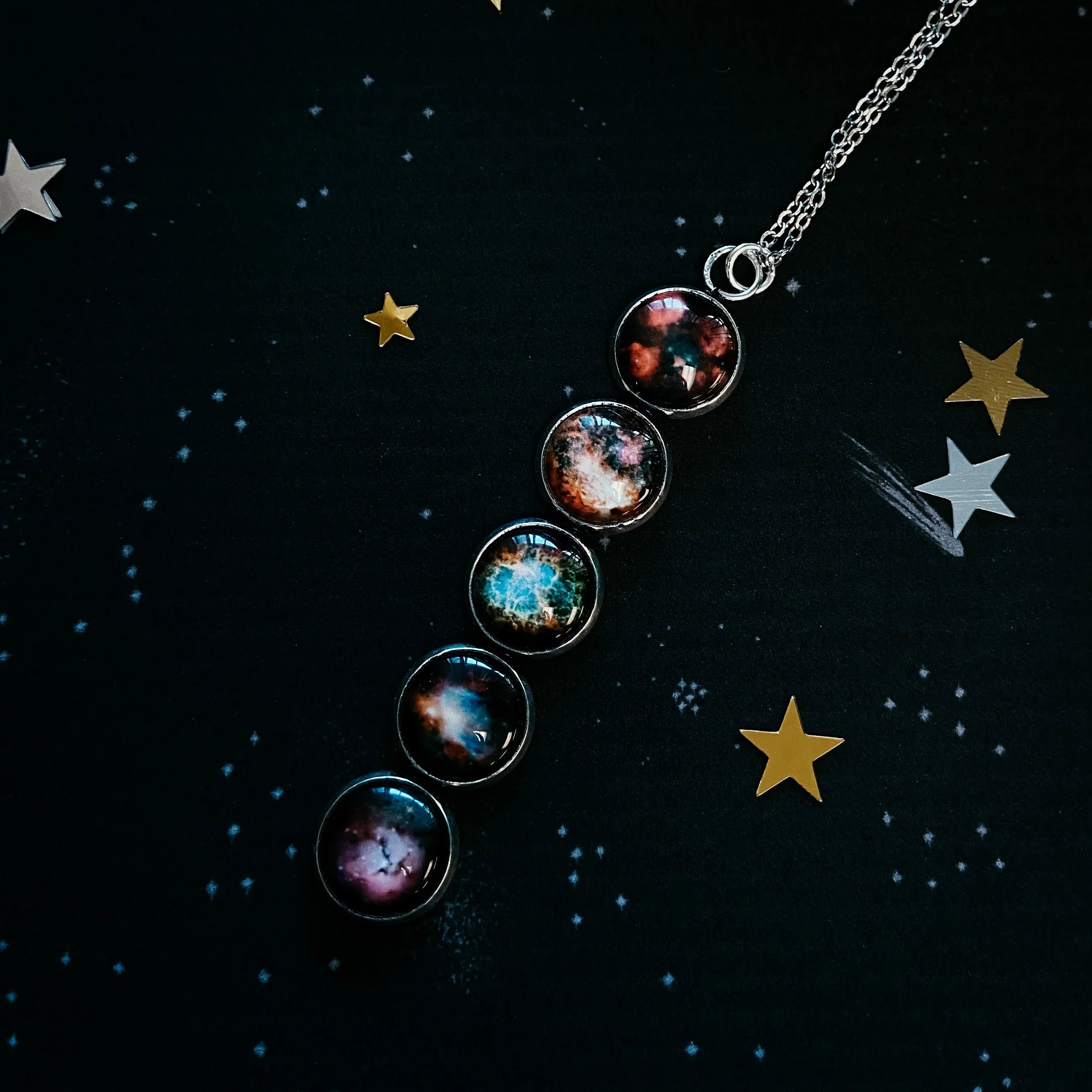 Galaxy-themed pendant necklace with five colorful space orbs on star-patterned black background