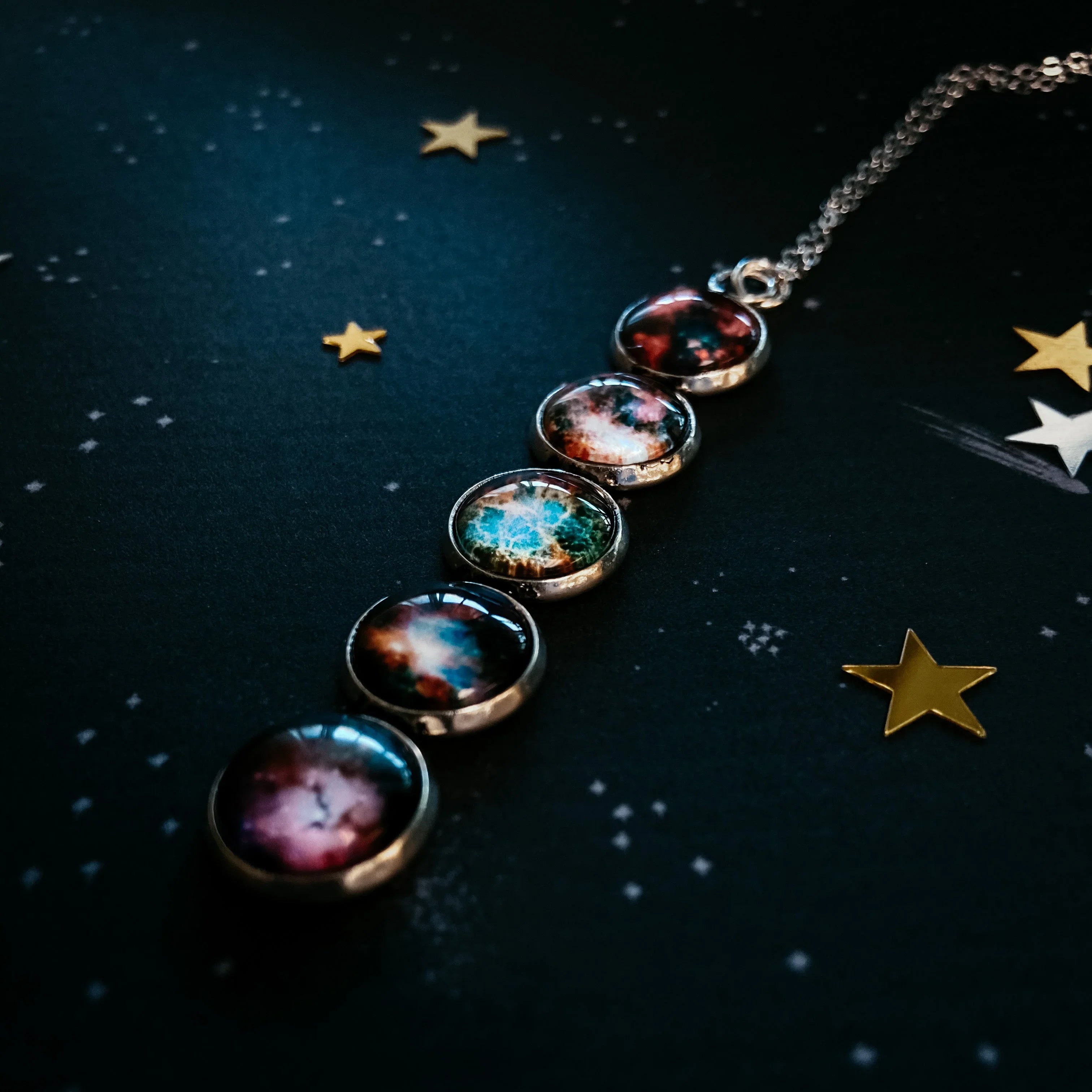 Galaxy-themed pendant necklace with colorful cosmic glass charms on dark starry background