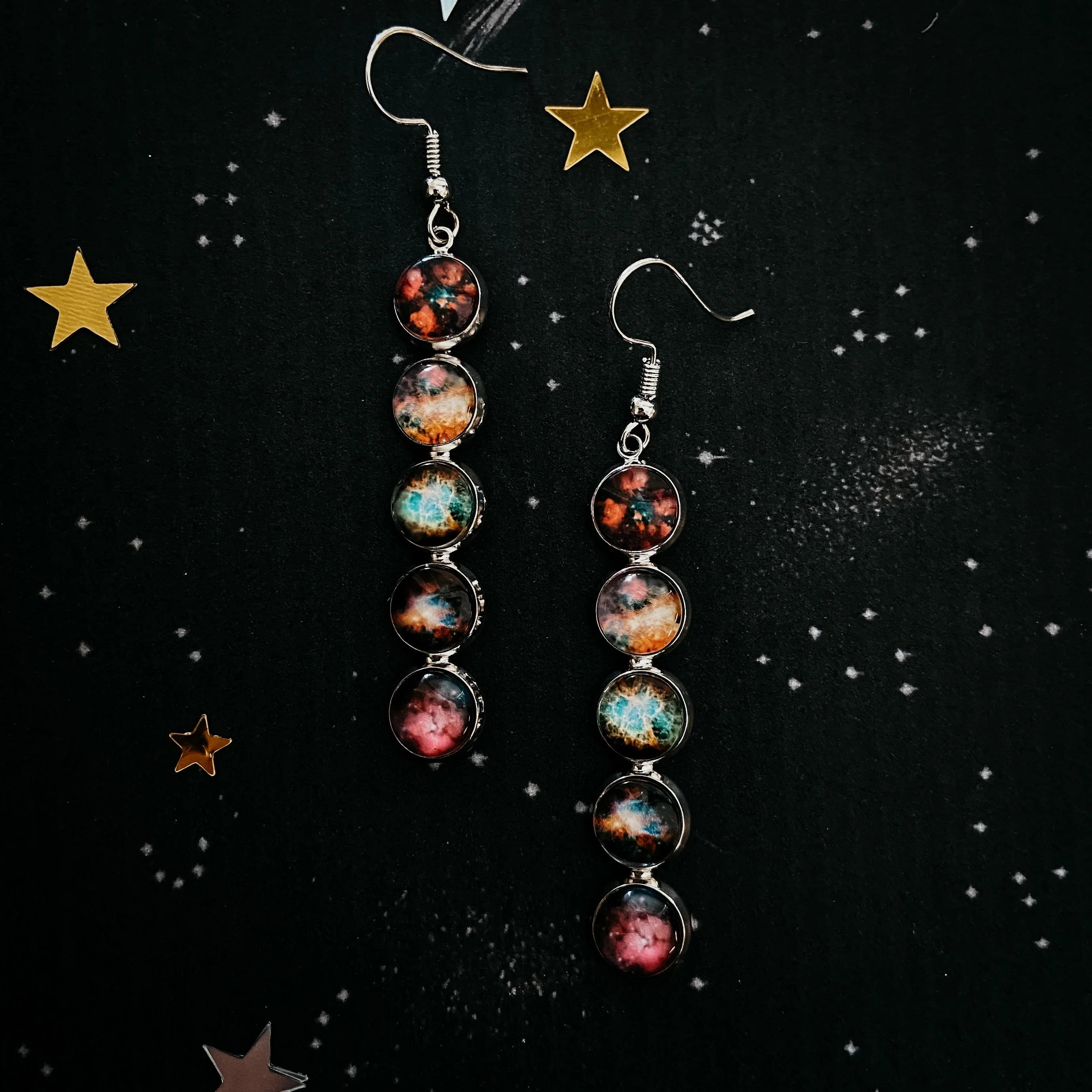 Galaxy-themed dangle earrings with colorful cosmic patterns on black starry background