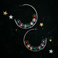 Silver crescent hoop earrings with colorful galaxy planet designs on black starry background