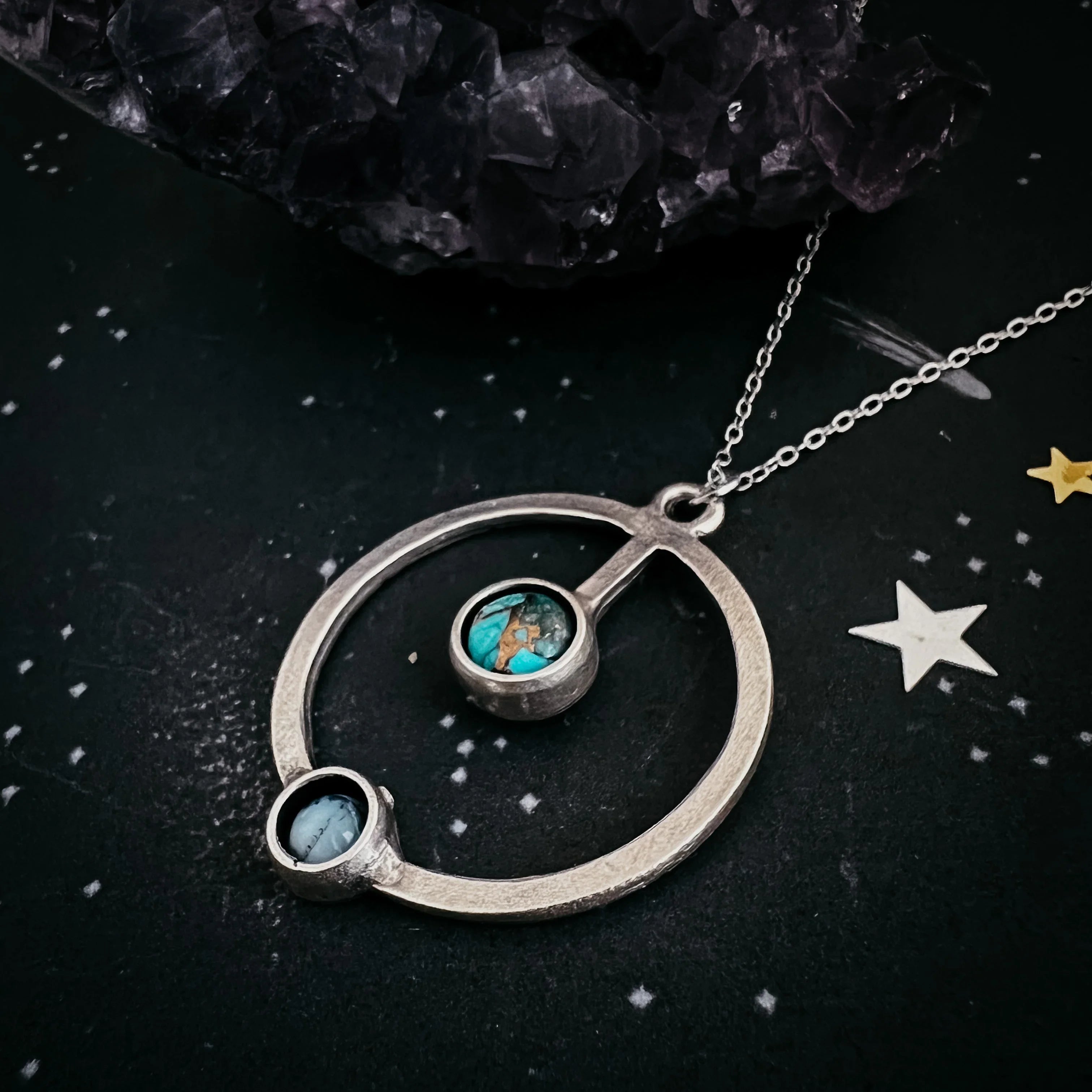 Silver circular pendant necklace with turquoise stones on starry black background and amethyst crystal