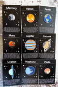 Solar system planet pins displayed on black cards with planetary facts and star illustrations