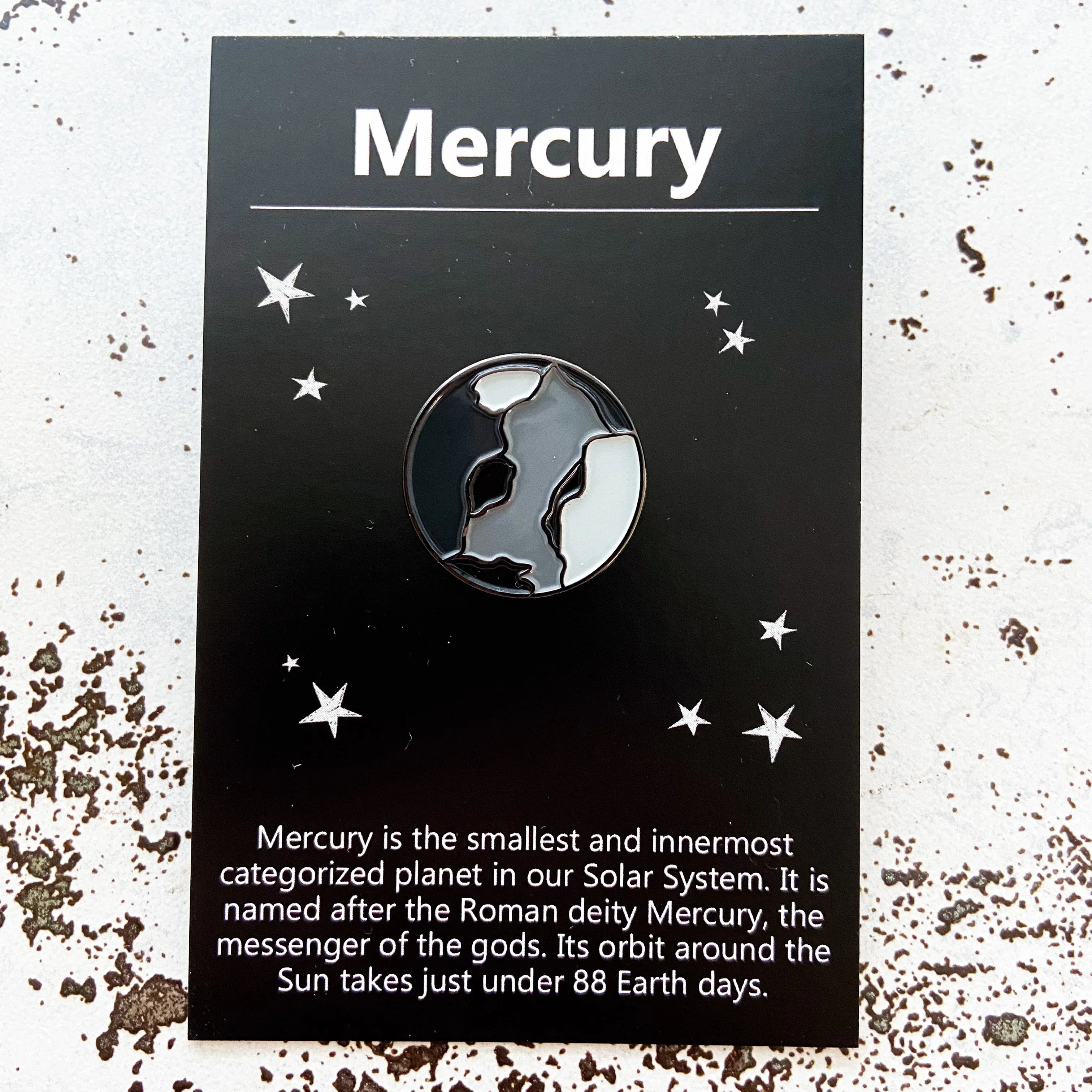 Enamel pin of planet Mercury on black card with stars and brief Mercury planet facts