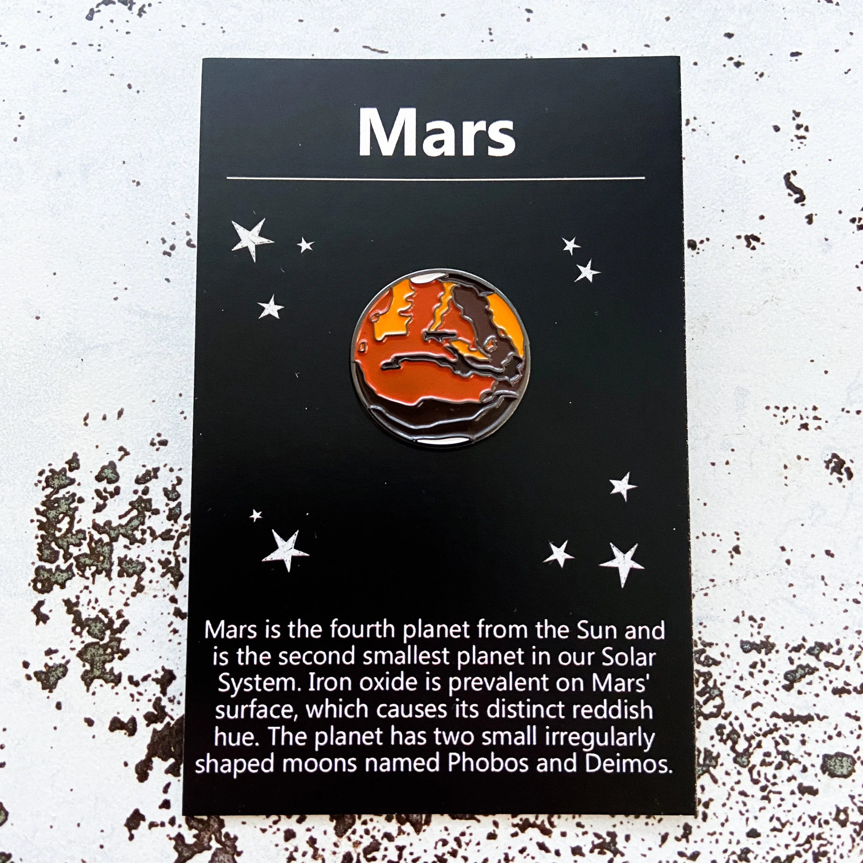 Mars enamel pin on black card with stars, describing Mars as fourth planet with iron oxide and two moons