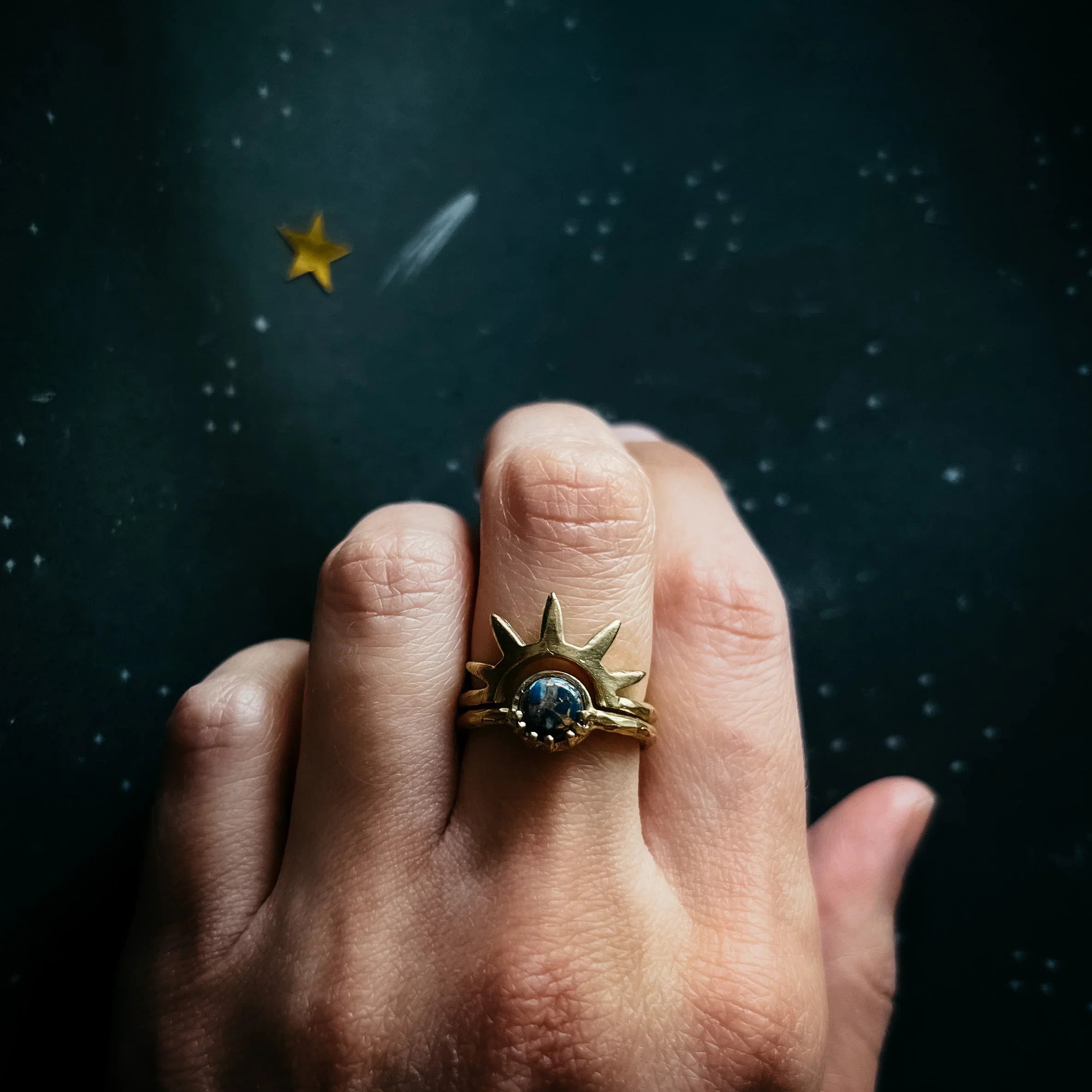 Gold cosmic sun ring with gemstone on hand, starry background, Qu!rk Boutique jewelry