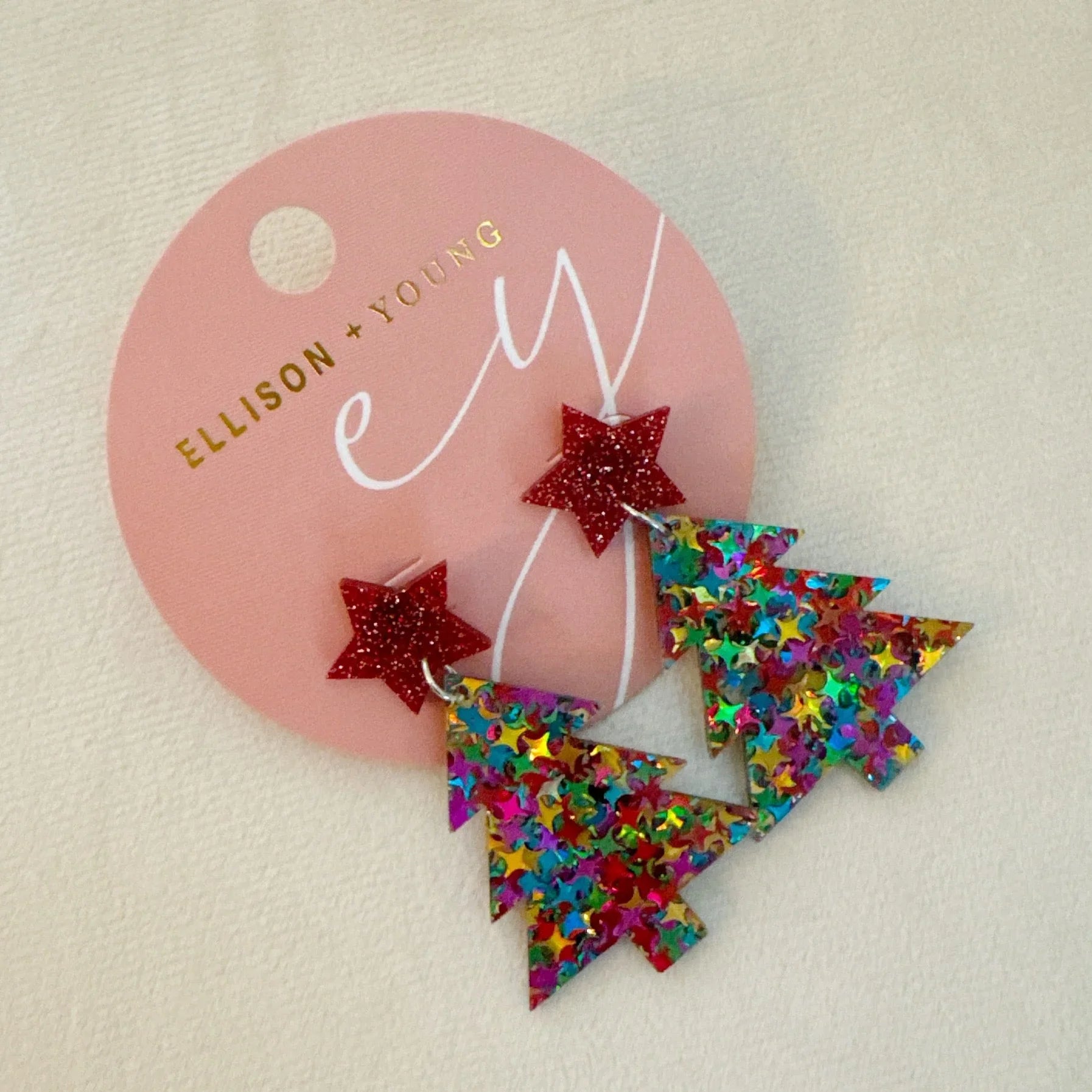 Ellison + Young multicolor glitter Christmas tree earrings with red star studs on pink card