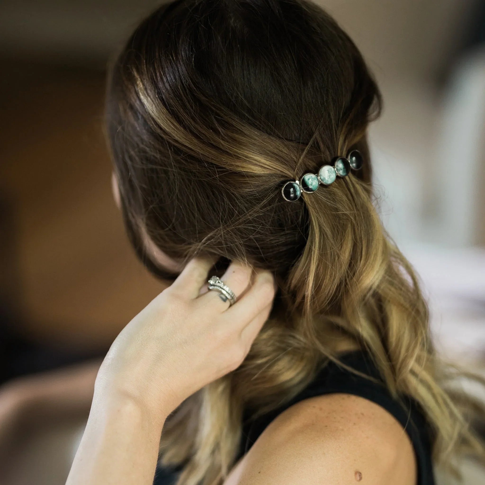 Woman with blonde balayage hair wearing a moon phase barrette and a silver ring