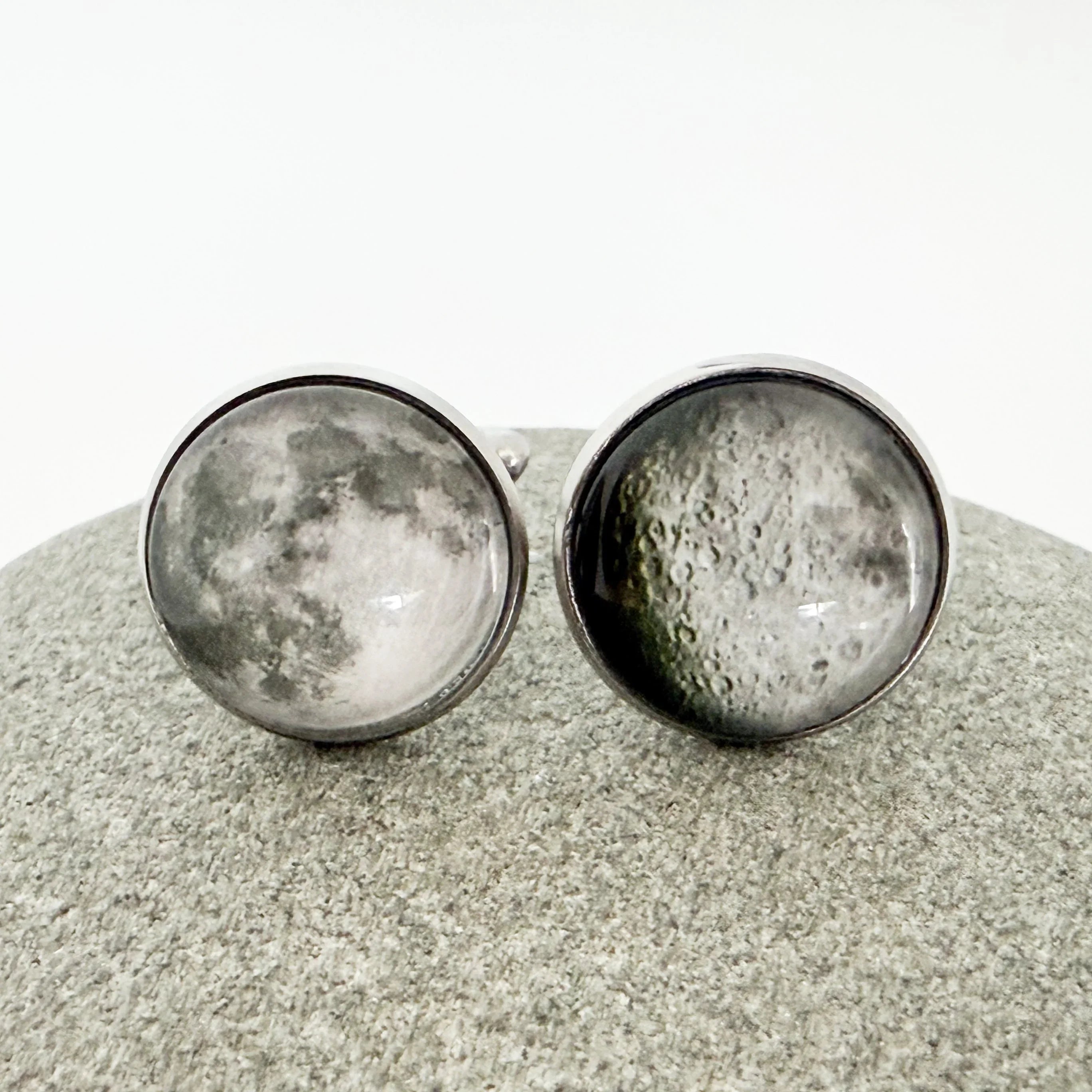 Round silver cufflinks featuring detailed full moon surface design on gray textured background