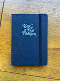 Black notebook with 'Say no to Fast Fashion' text on wood, eco-friendly Qu!rk Boutique gift.