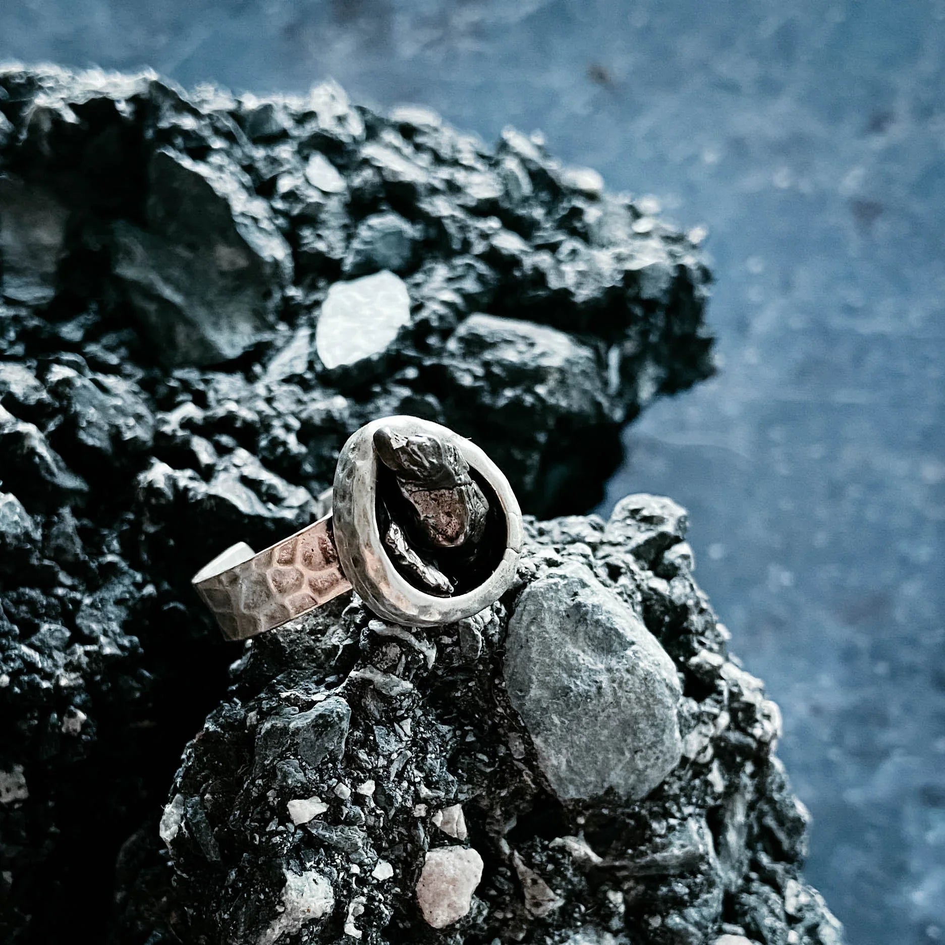 Handcrafted hammered metal ring on textured rock, Qu!rk Boutique artist-designed jewelry