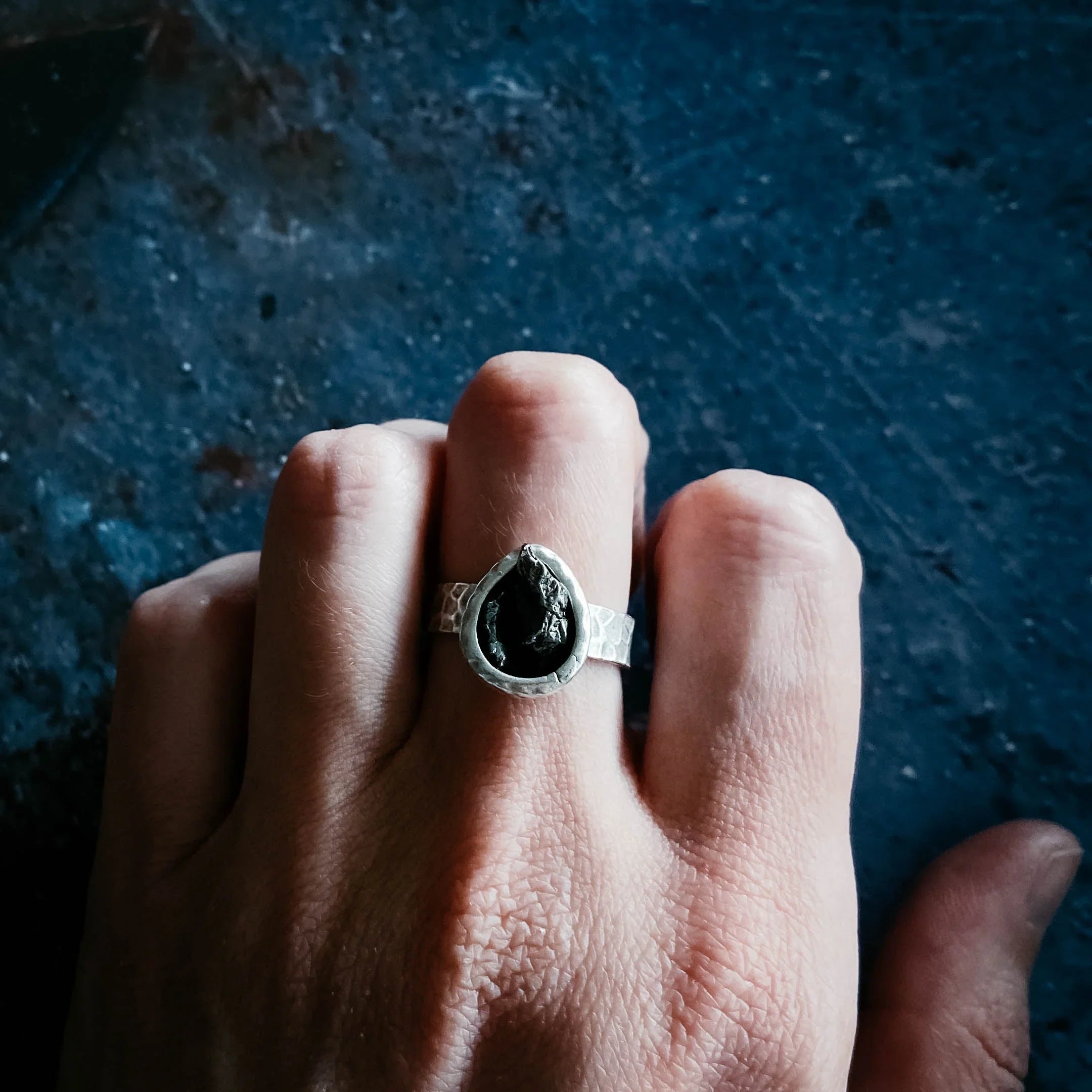 Hand wearing a silver ring with a teardrop-shaped black stone, artisan jewelry from Qu!rk Boutique