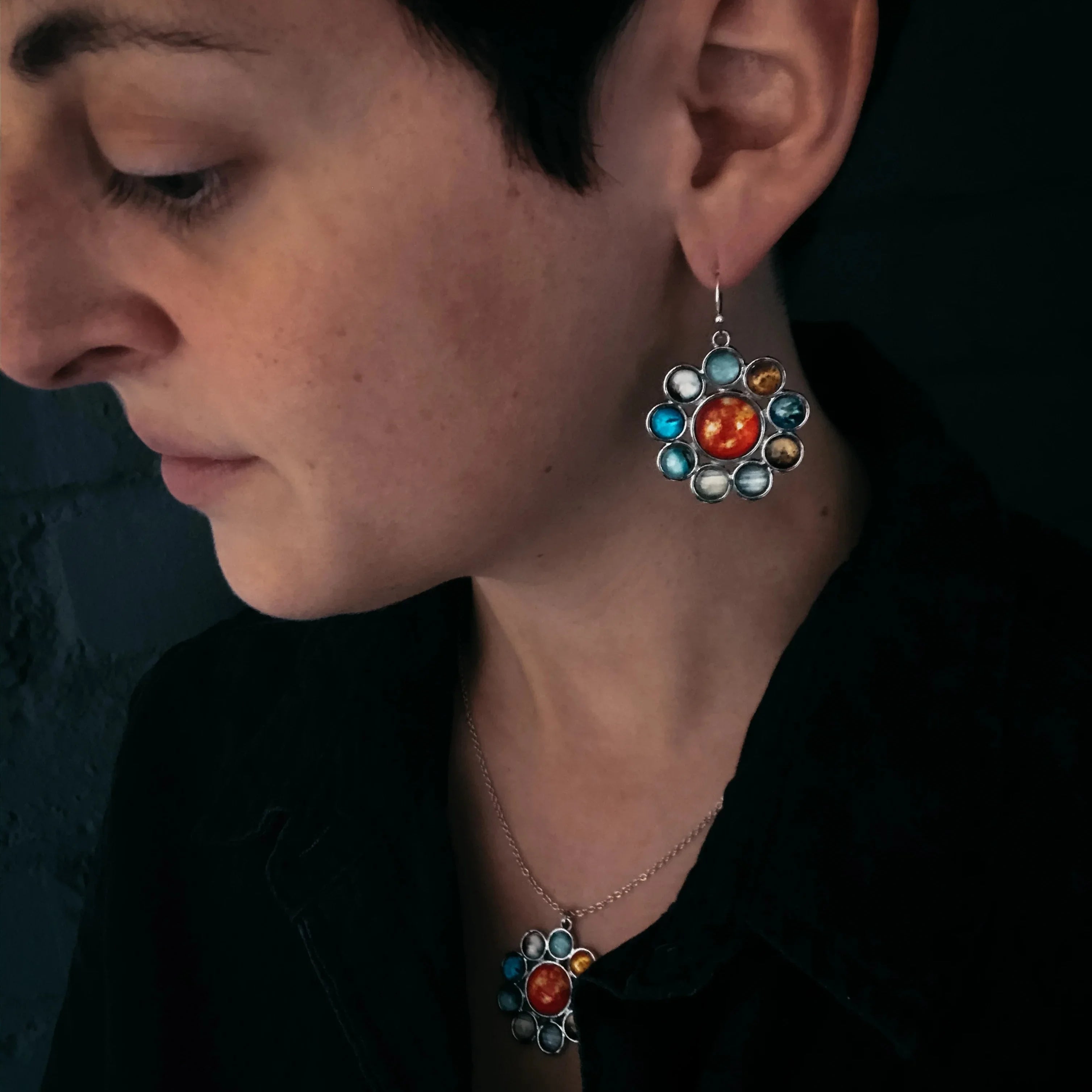 Woman wearing solar system-themed earrings and matching necklace with planet designs