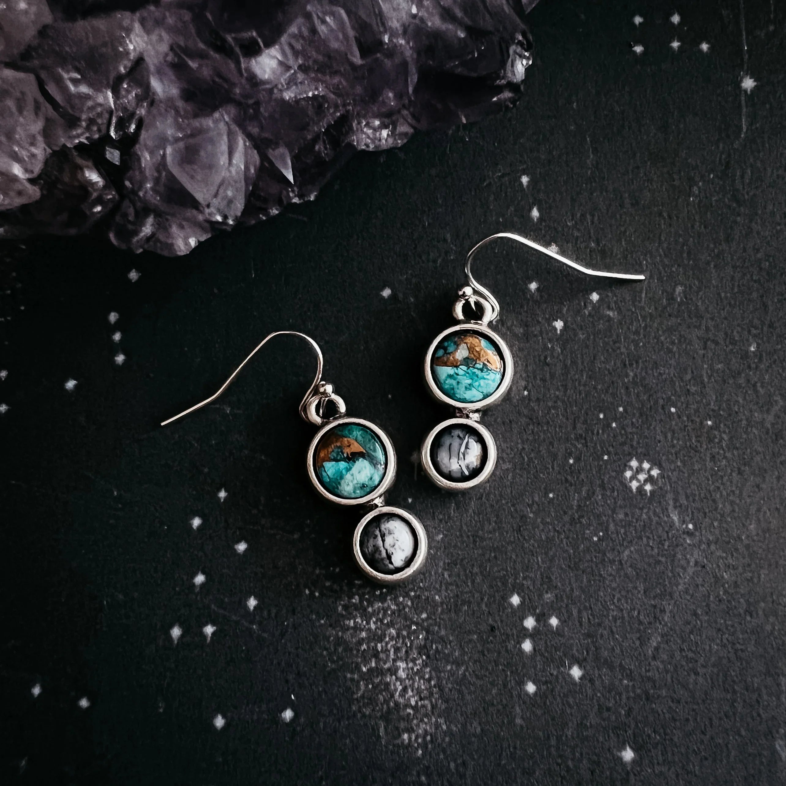 Silver dangle earrings with turquoise and black white stones on black starry background with amethyst crystal