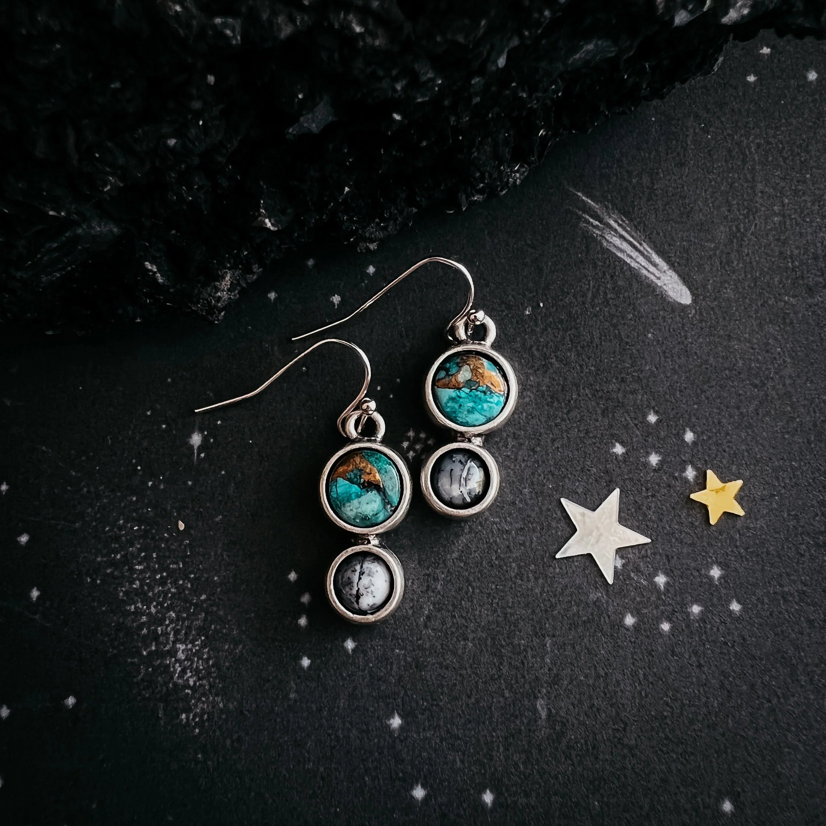Silver dangle earrings with turquoise and black stones on starry black background