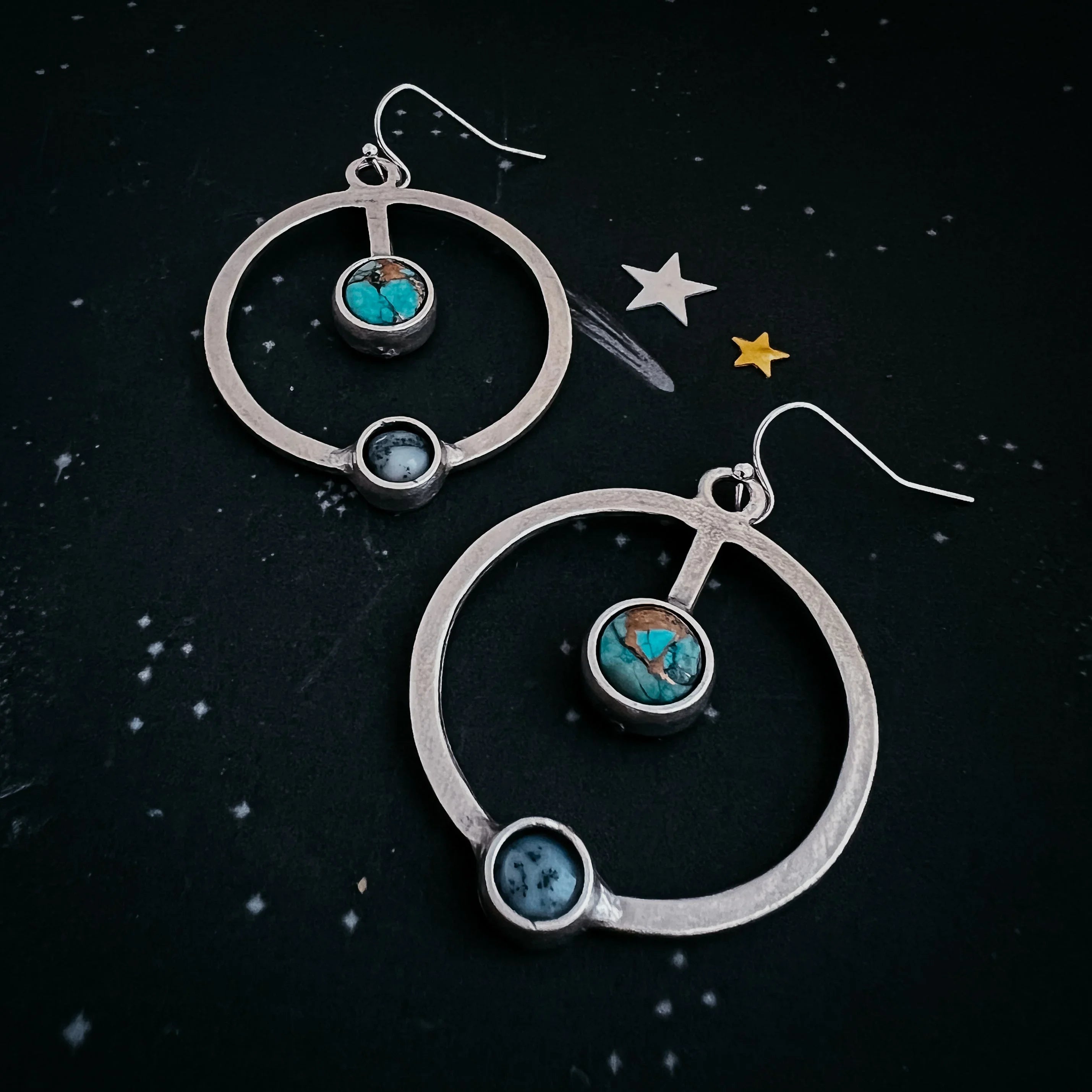 Silver hoop earrings with turquoise and blue stone accents on starry black background