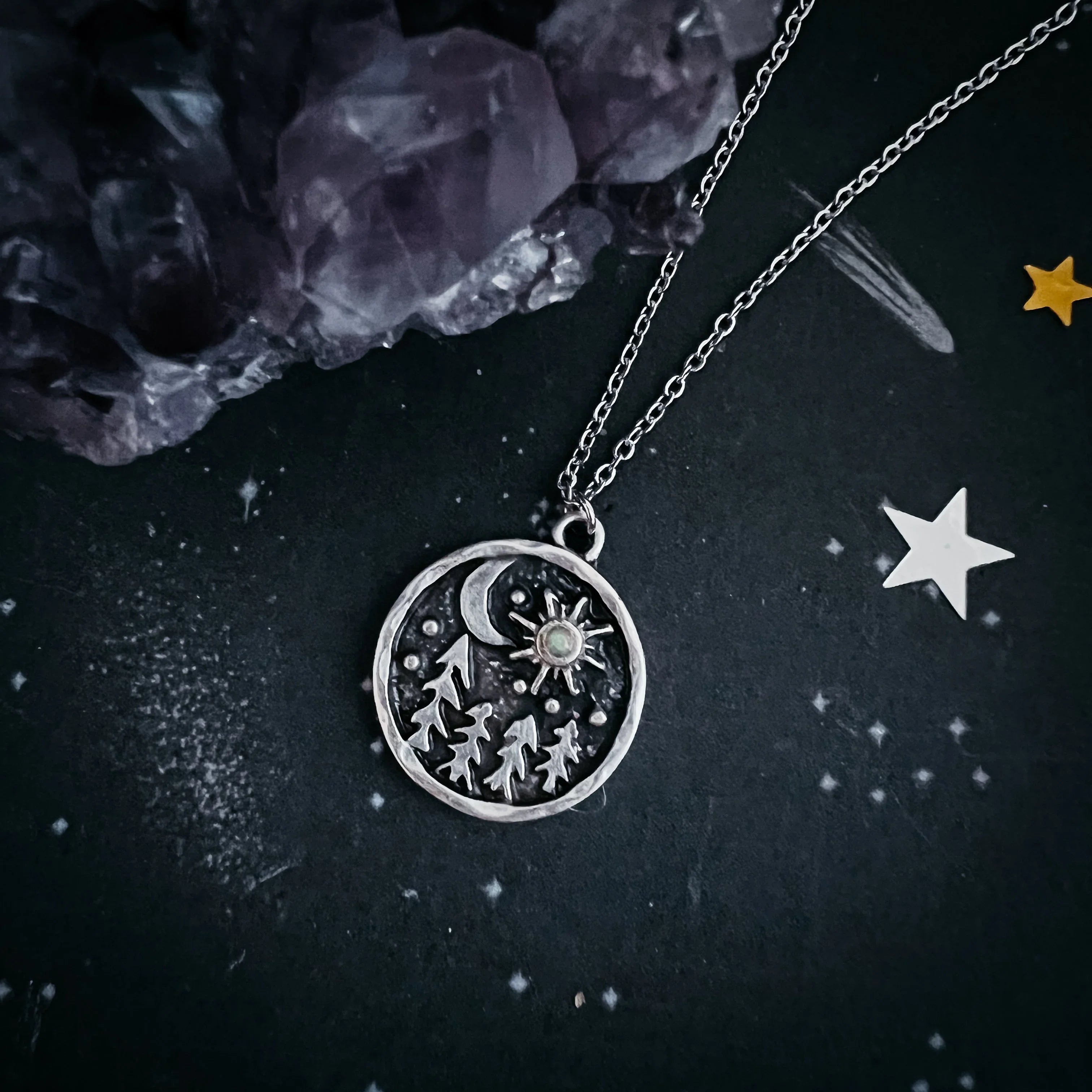 Cosmic forest-themed silver necklace with moon and sun pendant on a celestial background