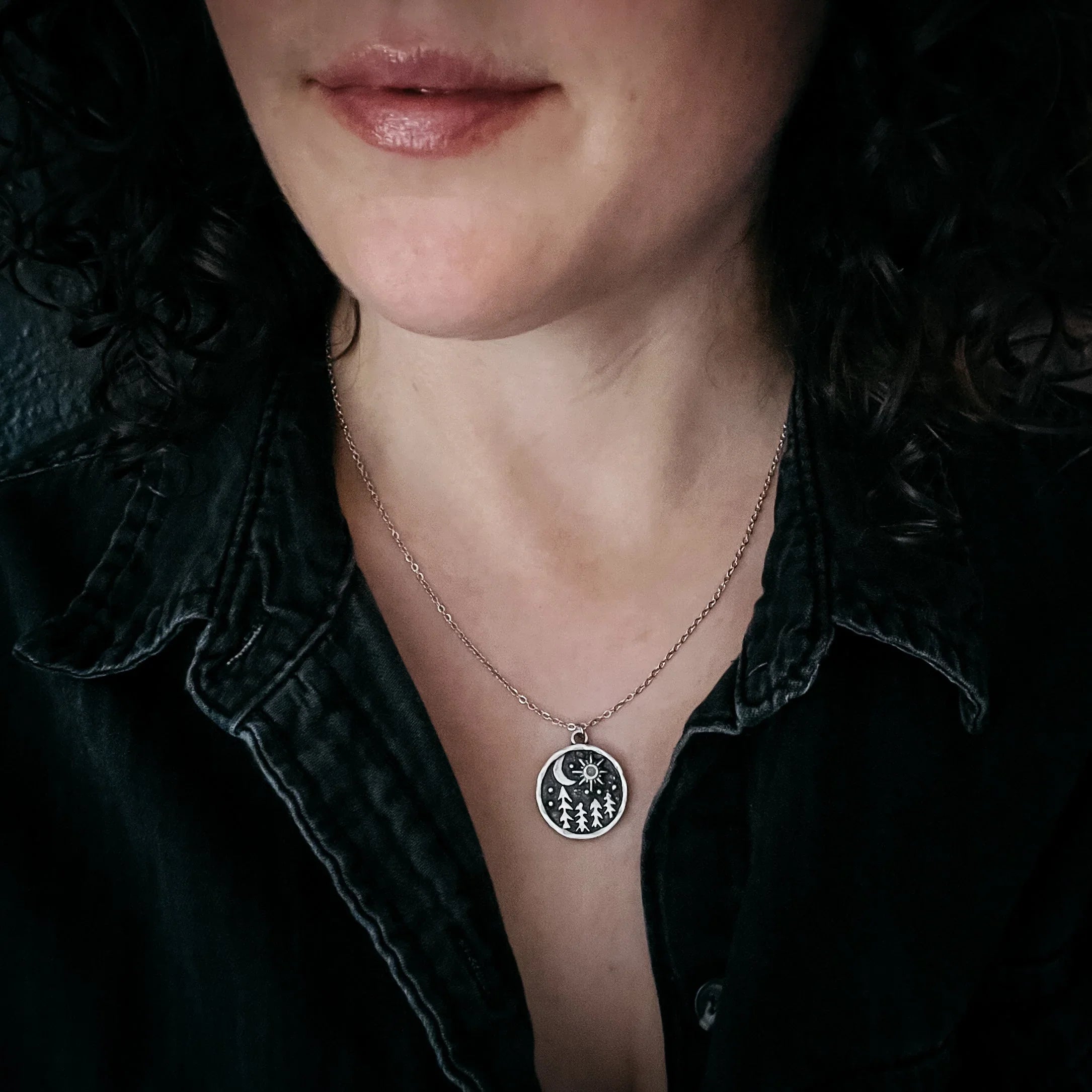 Woman wearing artist-designed forest and moon charm necklace from Qu!rk Boutique.