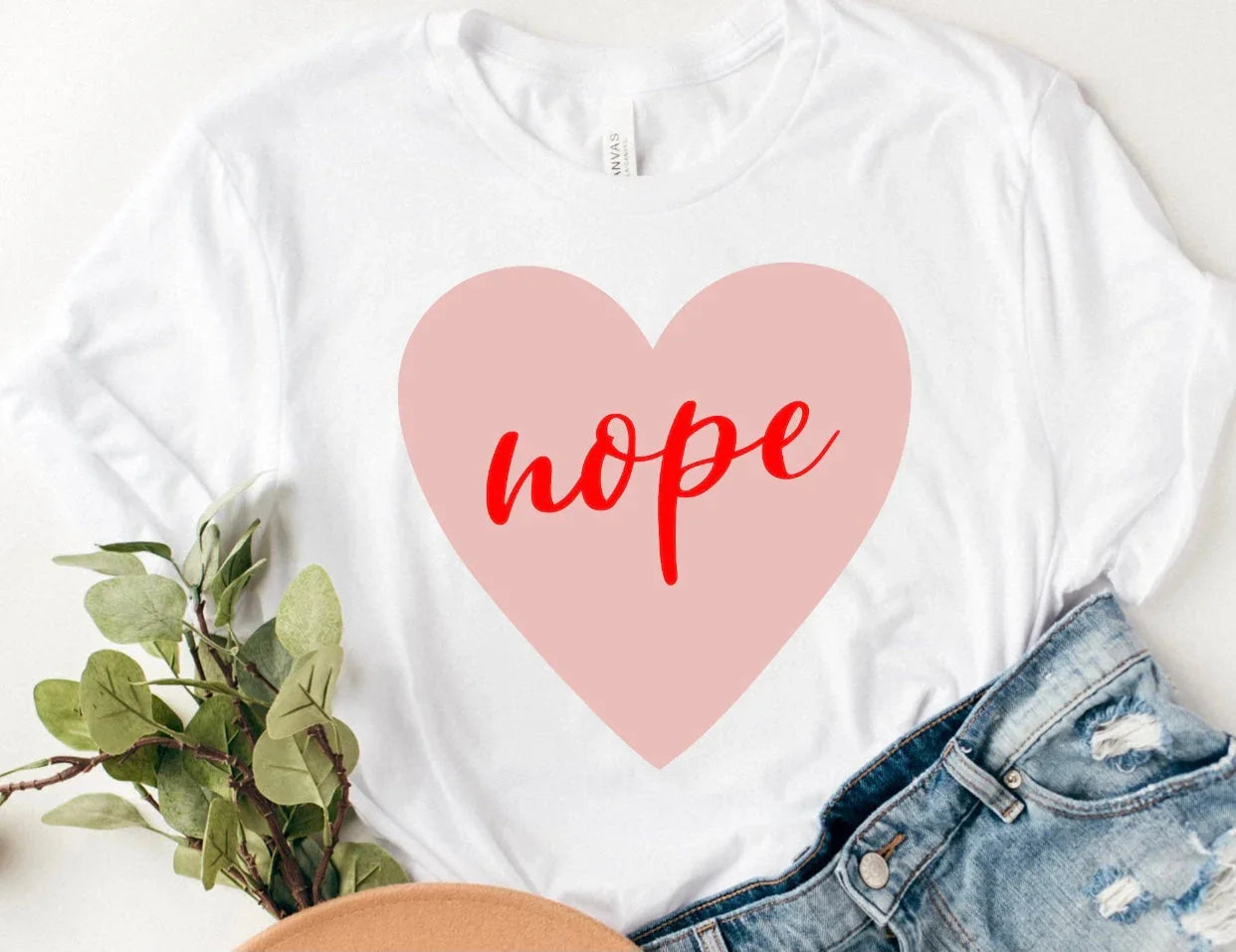 White graphic tee with pink heart and red 'nope' text, styled with denim by Qu!rk Boutique