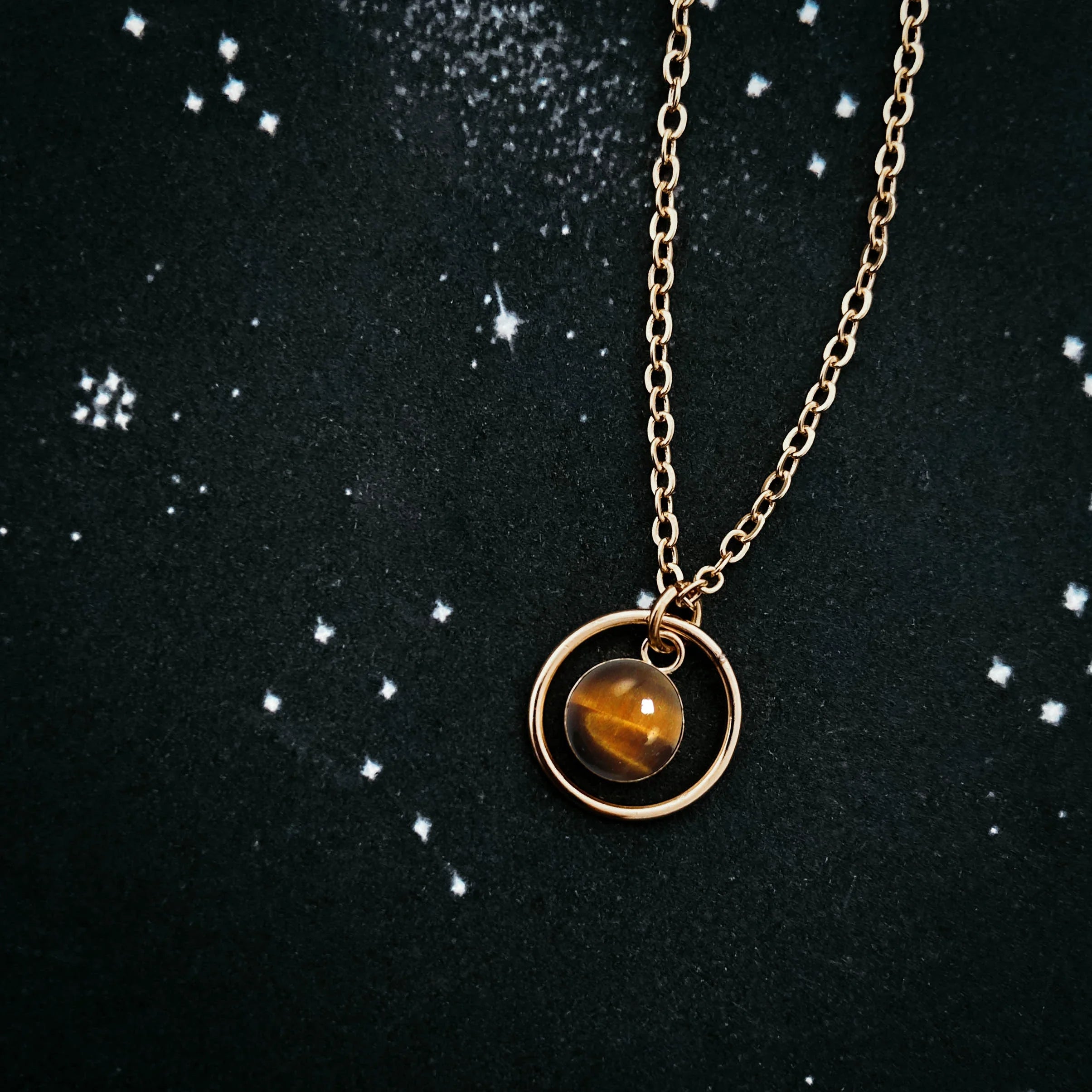 Gold pendant necklace with amber stone on cosmic starry background, Qu!rk Boutique jewelry