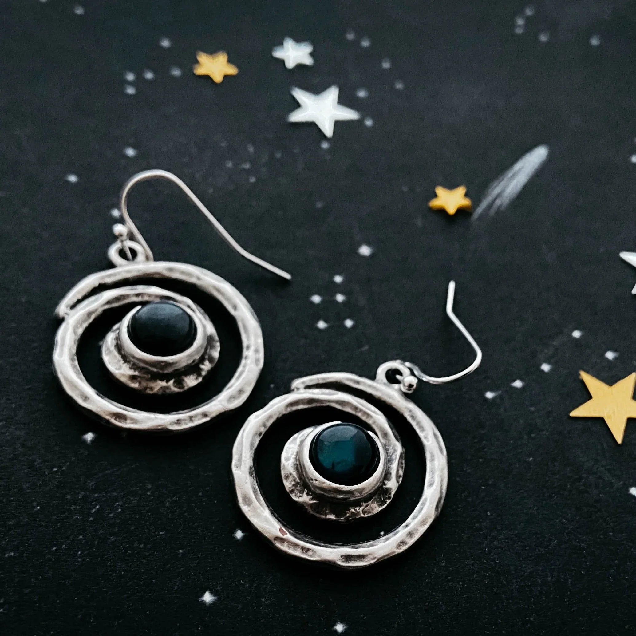 Handcrafted cosmic spiral earrings with dark center stones on starry black background, Qu!rk Boutique