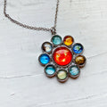 Silver necklace pendant featuring a solar system design with colorful planet glass cabochons on white surface