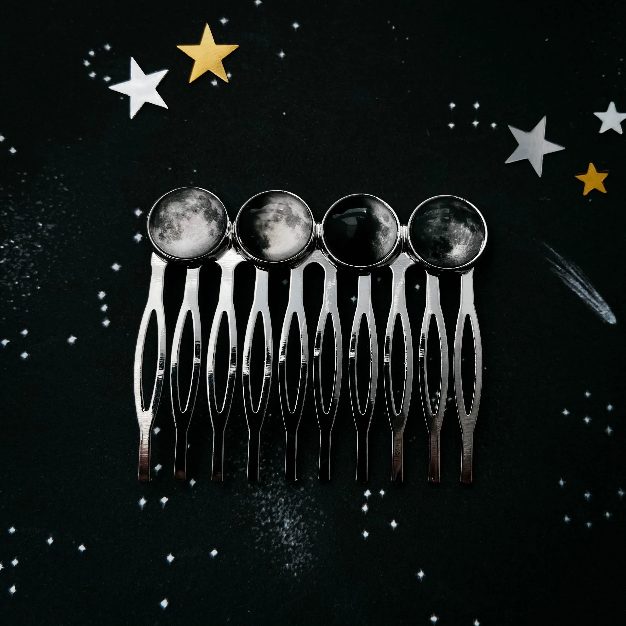 Silver hair comb with four phases of the moon designs on a starry night sky background