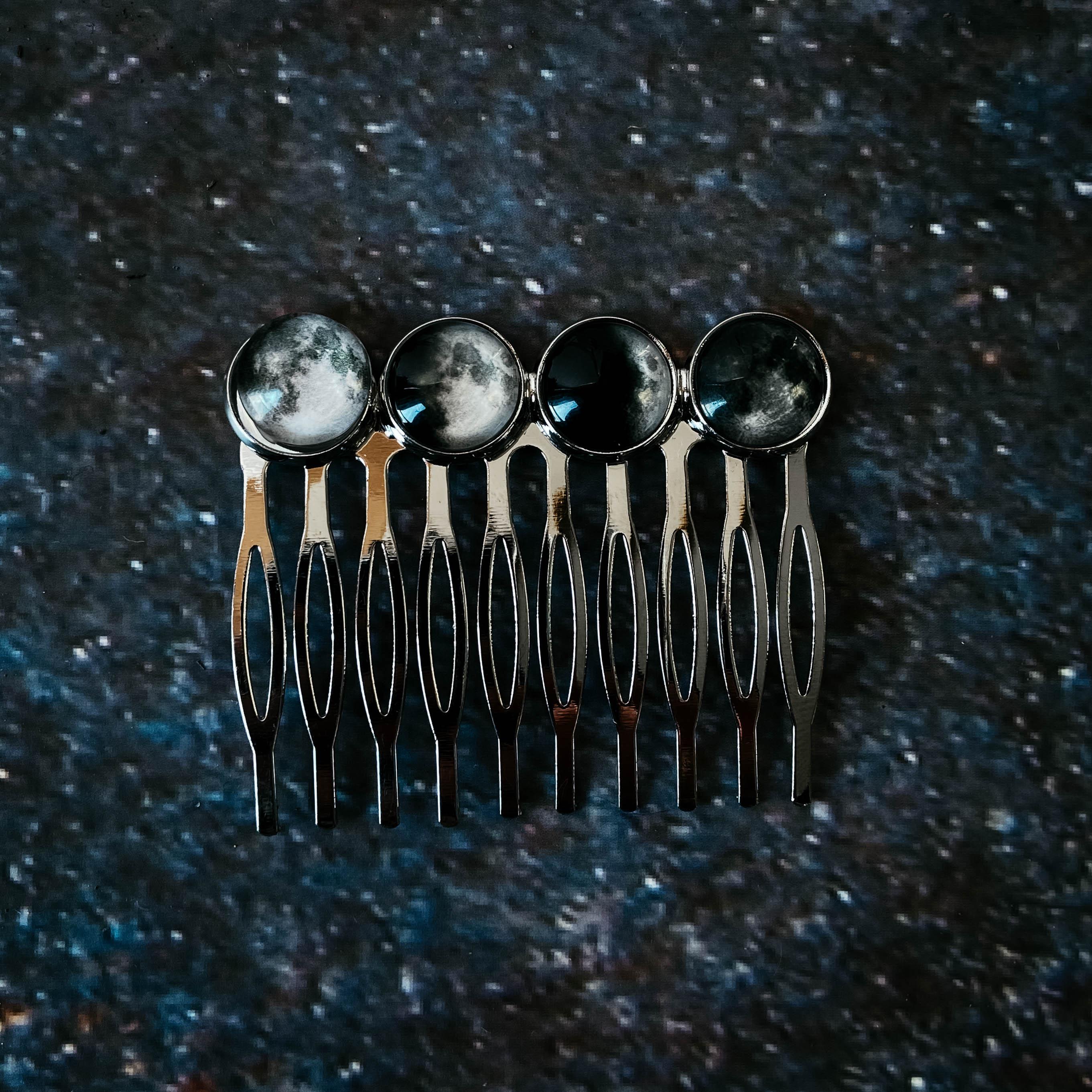 Silver hair comb with four moon phase glass cabochons on dark textured background
