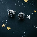 Handcrafted cosmic-inspired stud earrings on a starry black background at Qu!rk Boutique