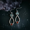 Handmade turquoise and red stone dangle earrings on cosmic background at Qu!rk Boutique