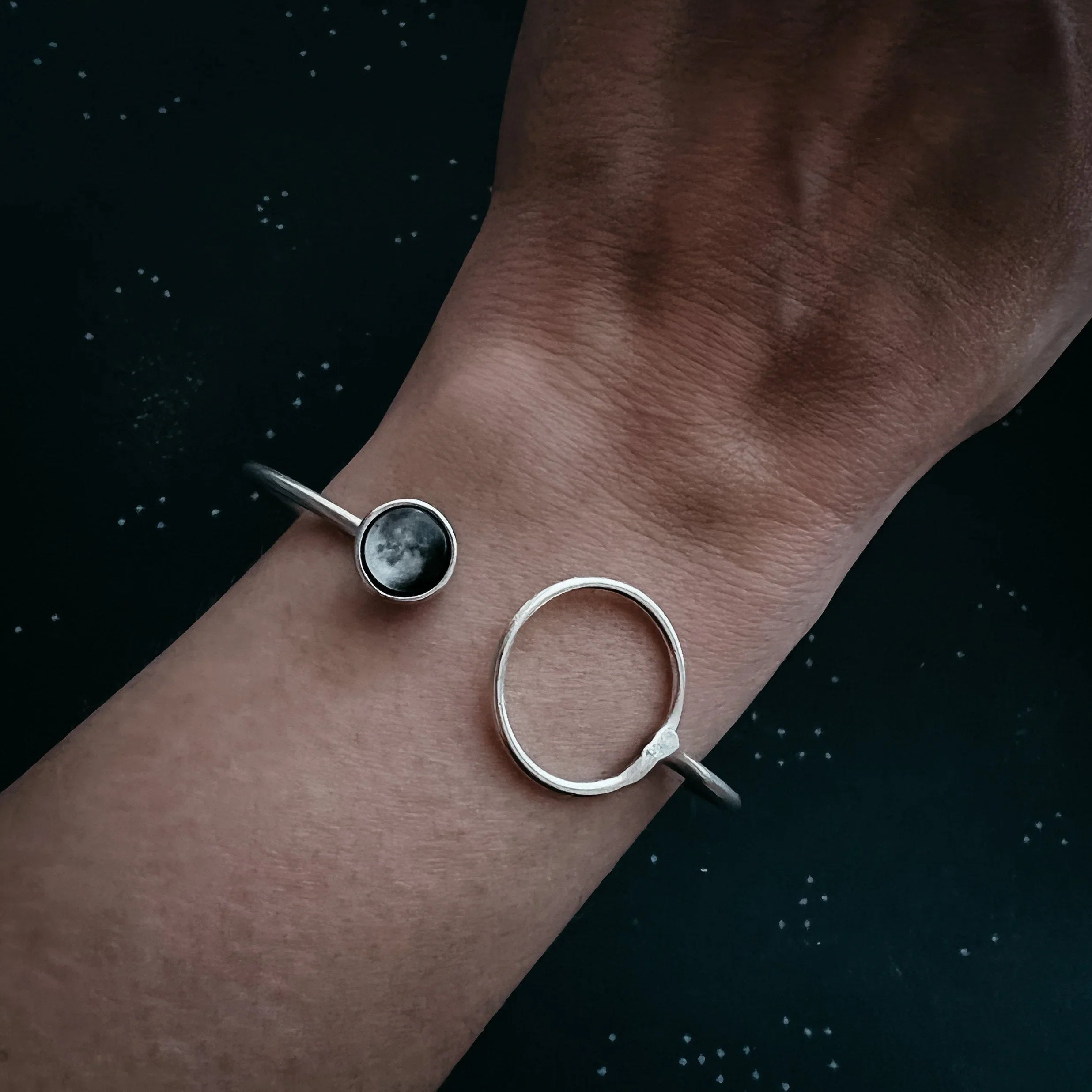 Hand wearing a silver moon phase cuff bracelet, cosmic jewelry from Qu!rk Boutique gift shop.