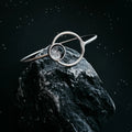 Cosmic silver bracelet with moonstone accent on dark rock, Qu!rk artist-designed jewelry