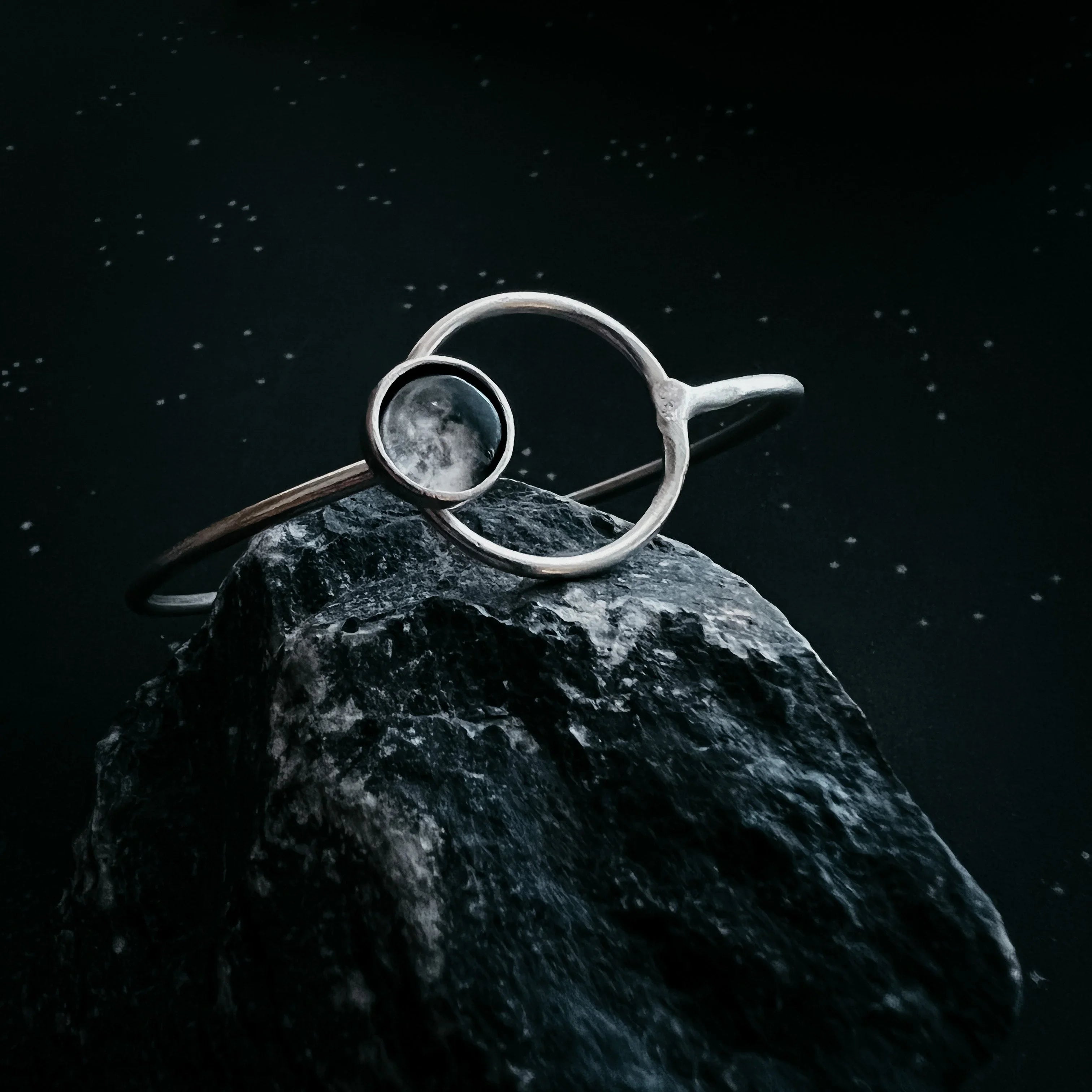 Silver cosmic-inspired bracelet with stone accent on black rock, Qu!rk Boutique jewelry