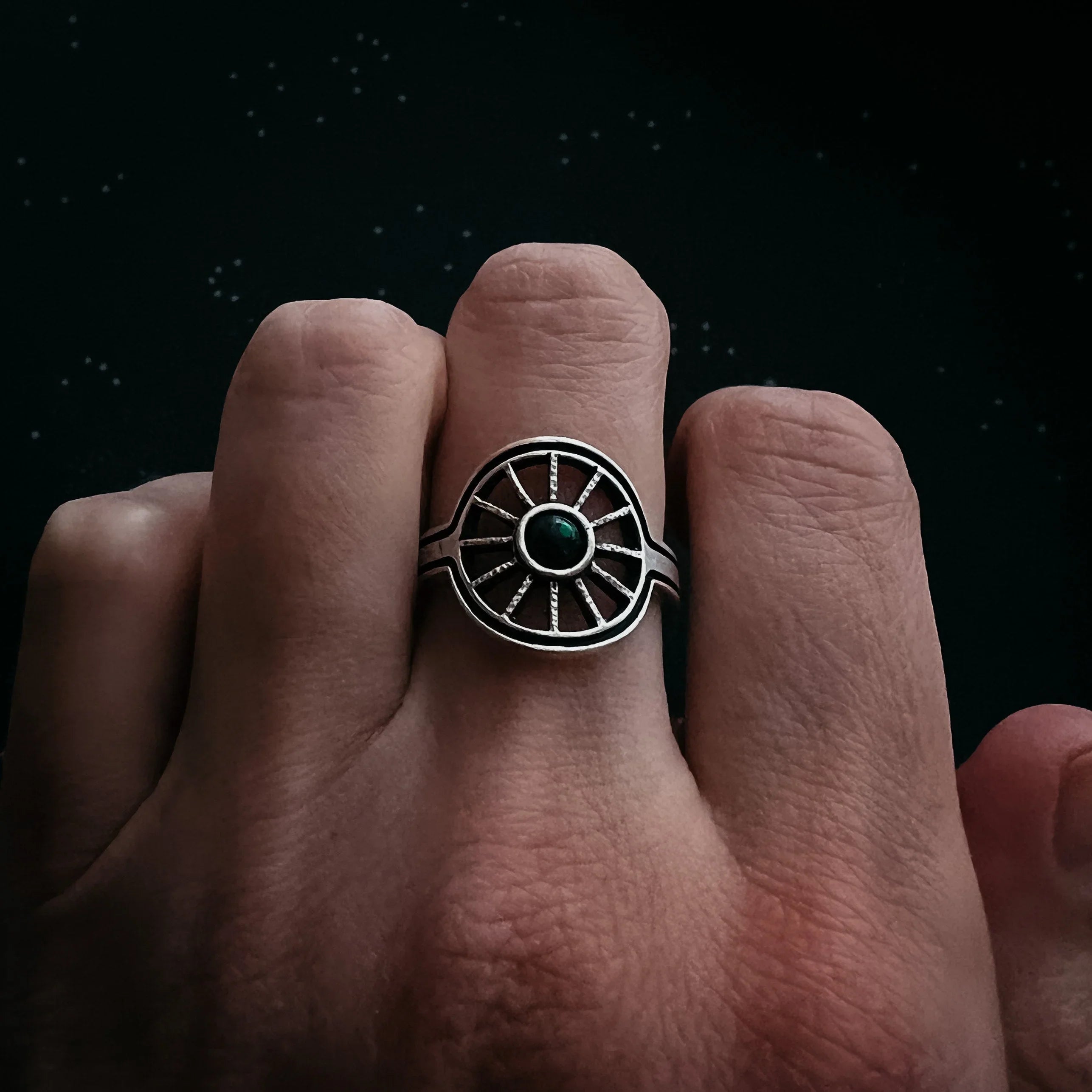 Hand wearing a cosmic-inspired silver ring with green stone, Qu!rk Boutique jewelry
