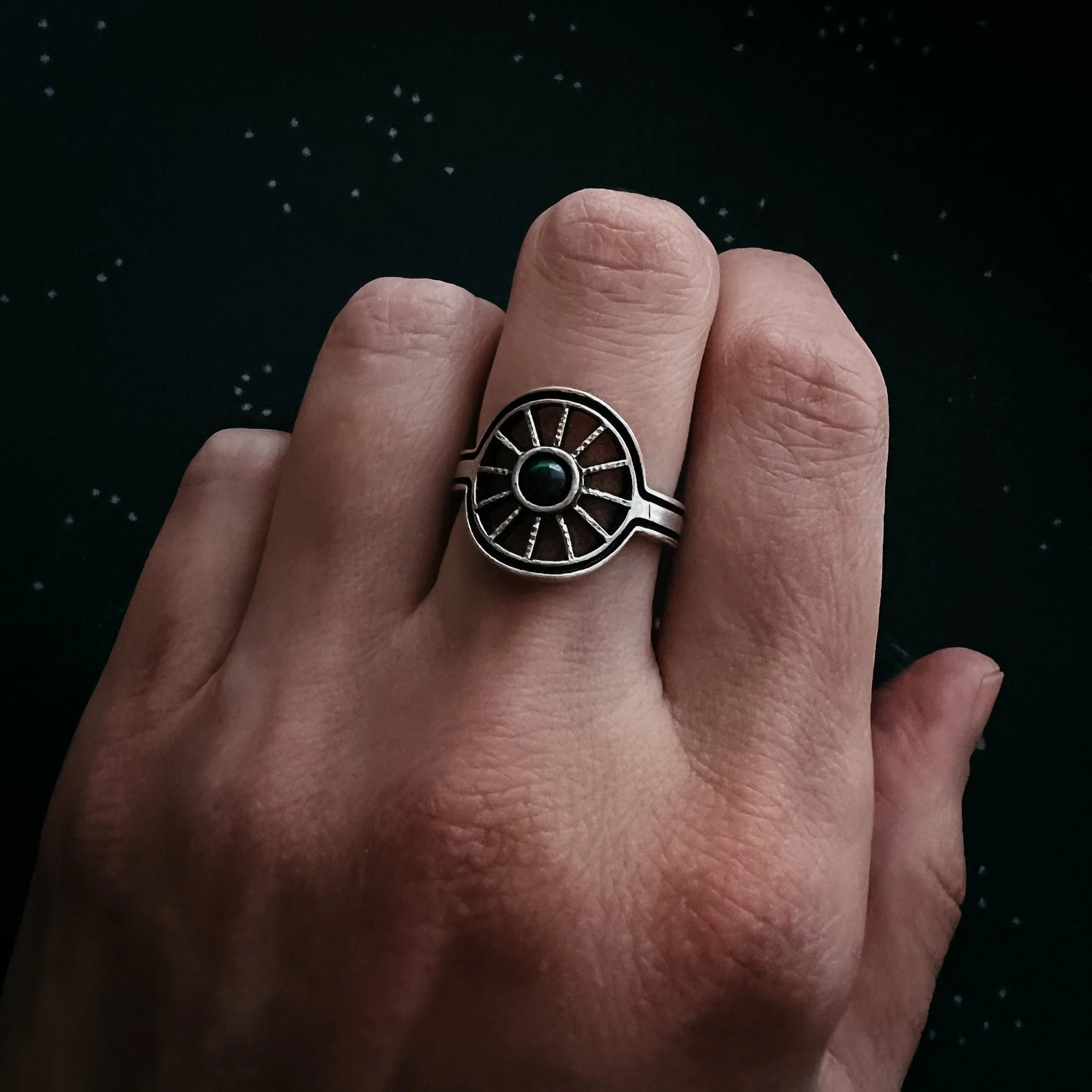 Hand wearing cosmic-inspired silver ring with black stone from Qu!rk Boutique