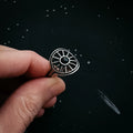 Hand holding cosmic-inspired silver ring with black stone, starry background, Qu!rk Boutique