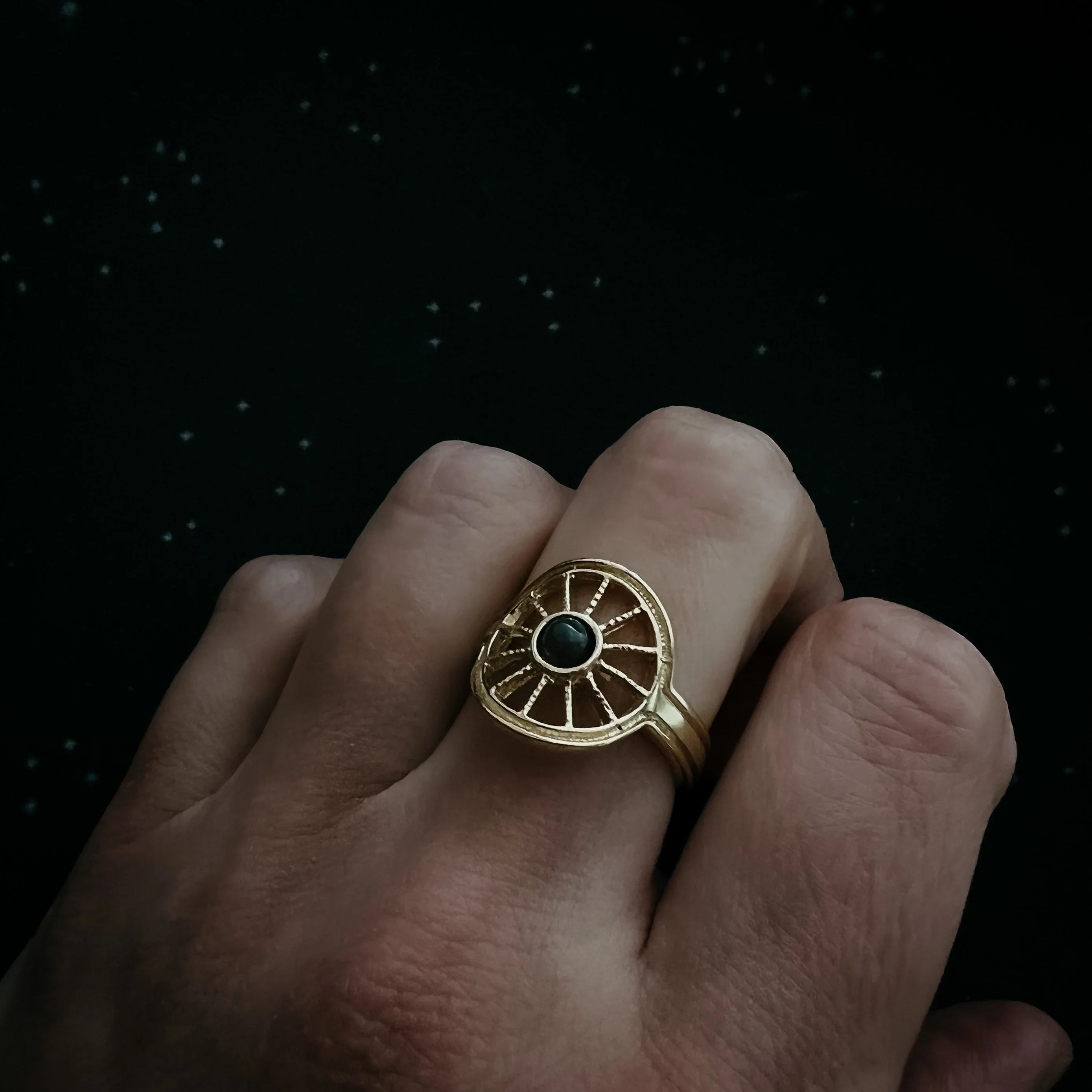 Gold cosmic-inspired statement ring with black stone on hand, Qu!rk Boutique jewelry