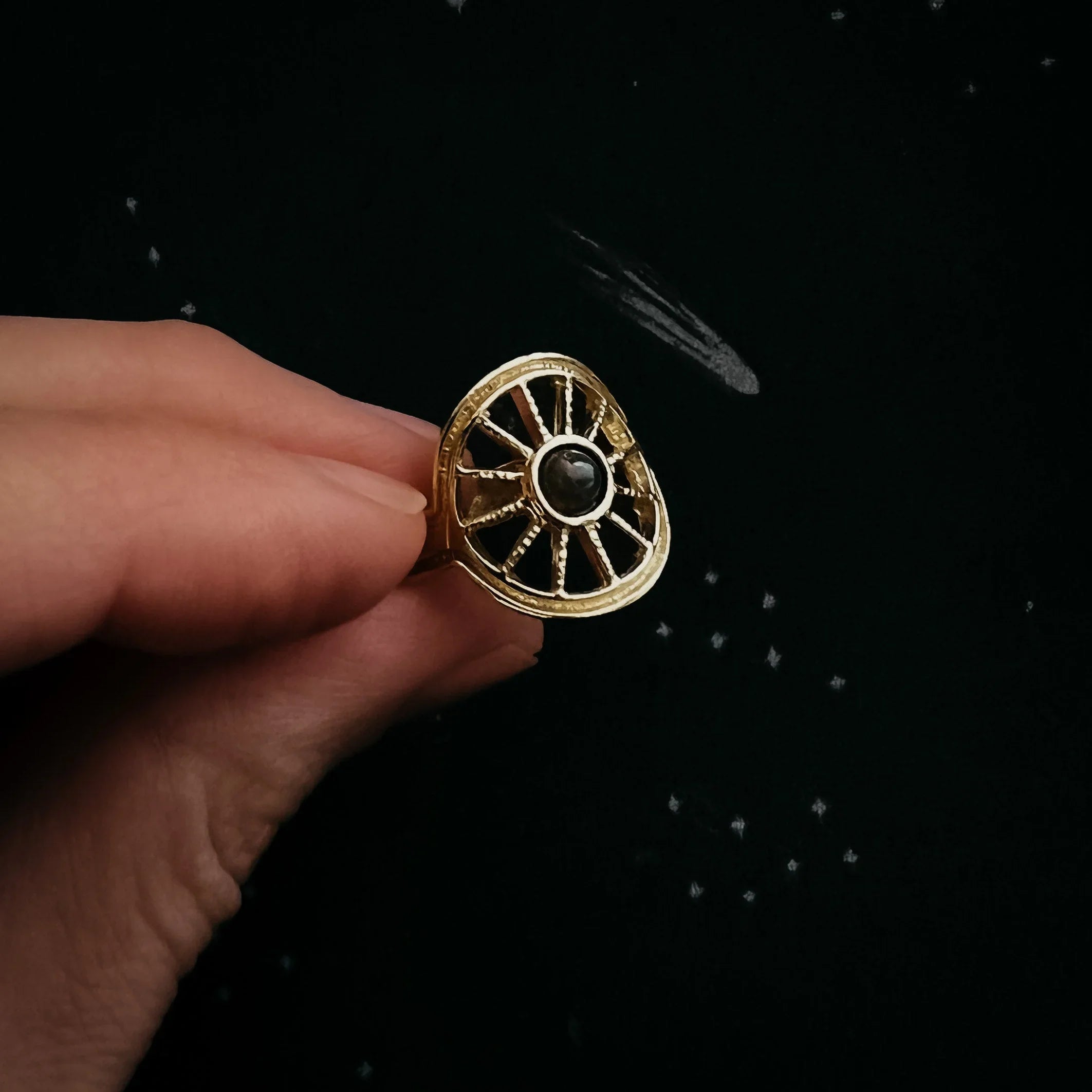 Hand holding gold cosmic-inspired artisan ring with black gemstone, Qu!rk Boutique jewelry