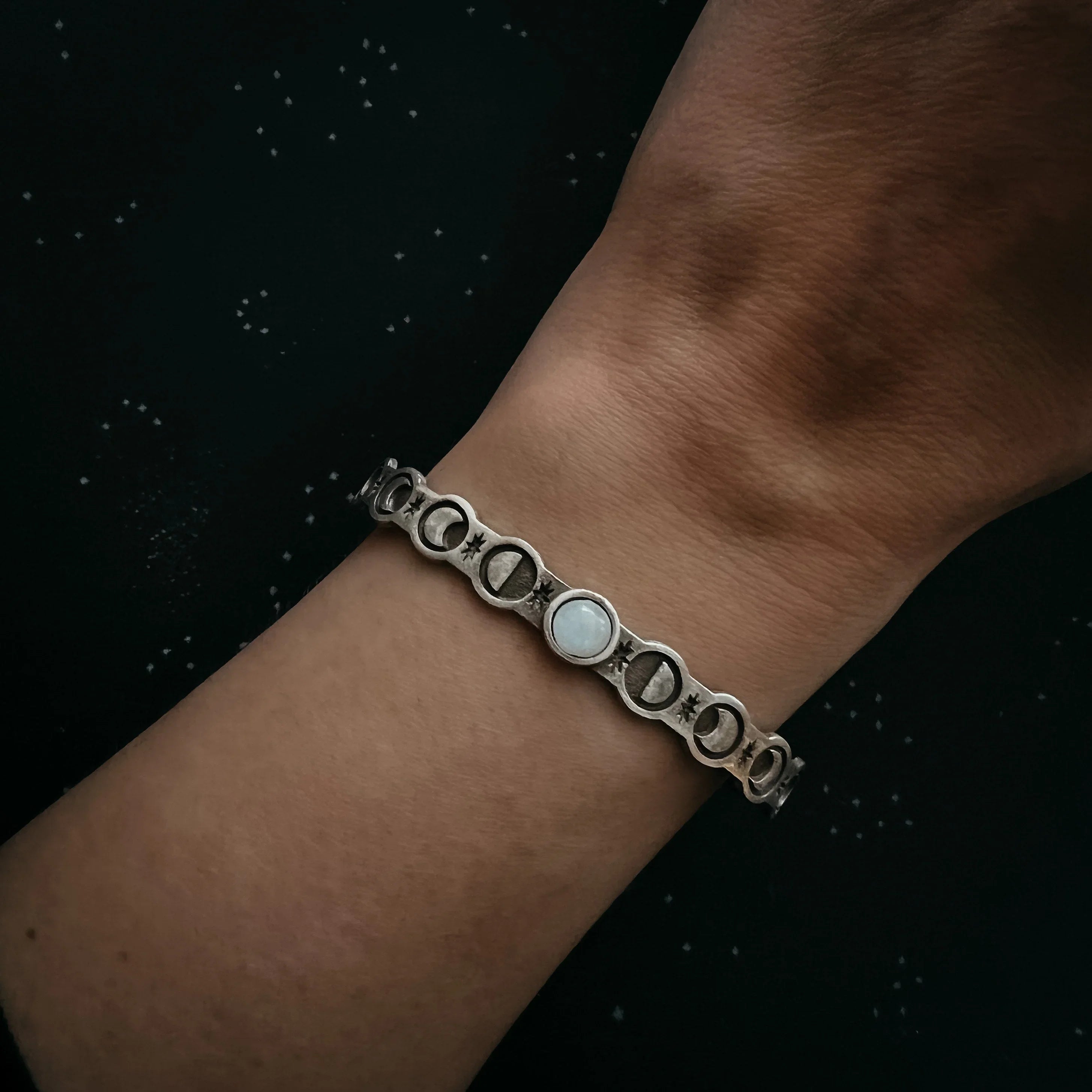 Hand wearing celestial moon phase bracelet, cosmic jewelry at Qu!rk Boutique & Gift Shop