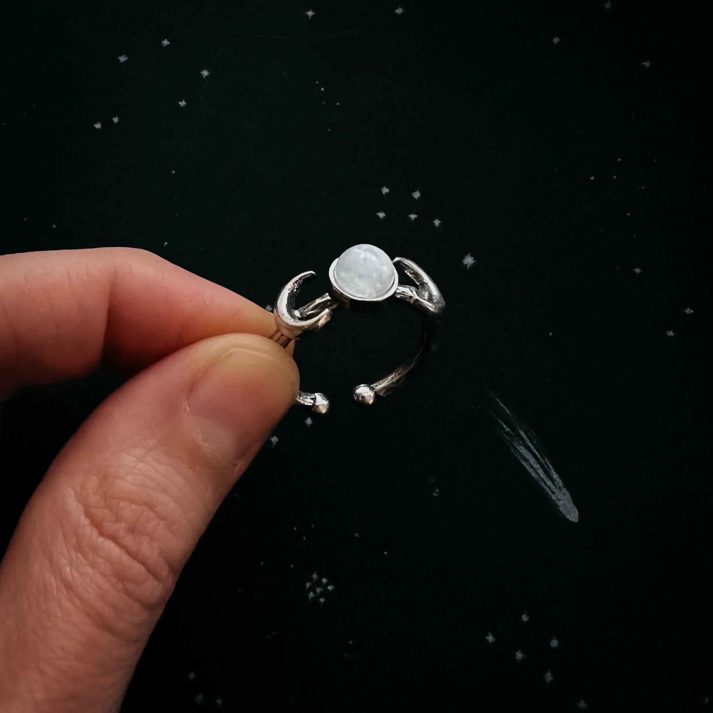 Hand holding a silver moonstone ring with celestial design, cosmic jewelry at Qu!rk Boutique