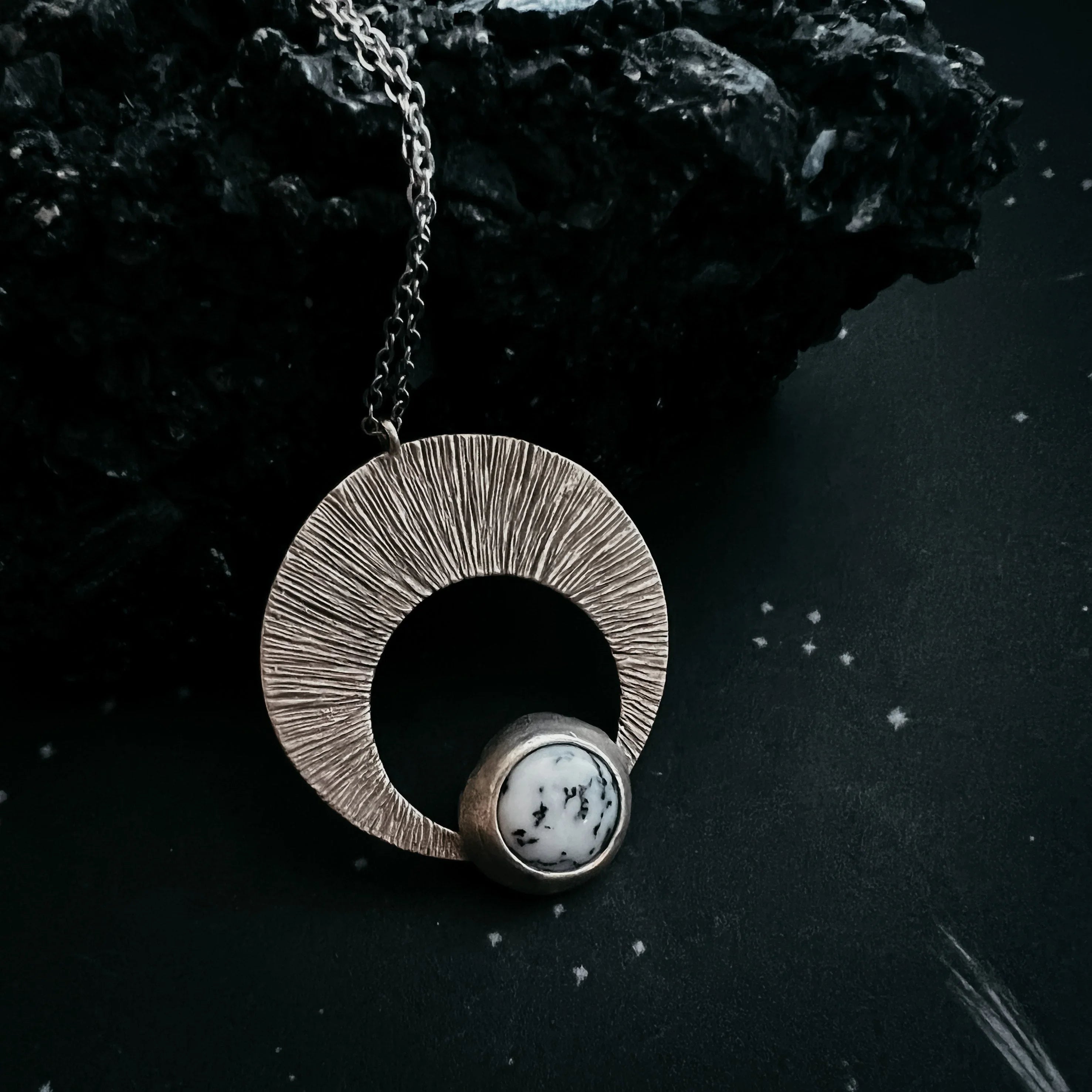 Artist-designed silver pendant necklace with circular textured ring and marble stone, cosmic style