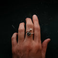 Hand wearing an artist-designed cosmic silver ring with black stone, Qu!rk Boutique jewelry