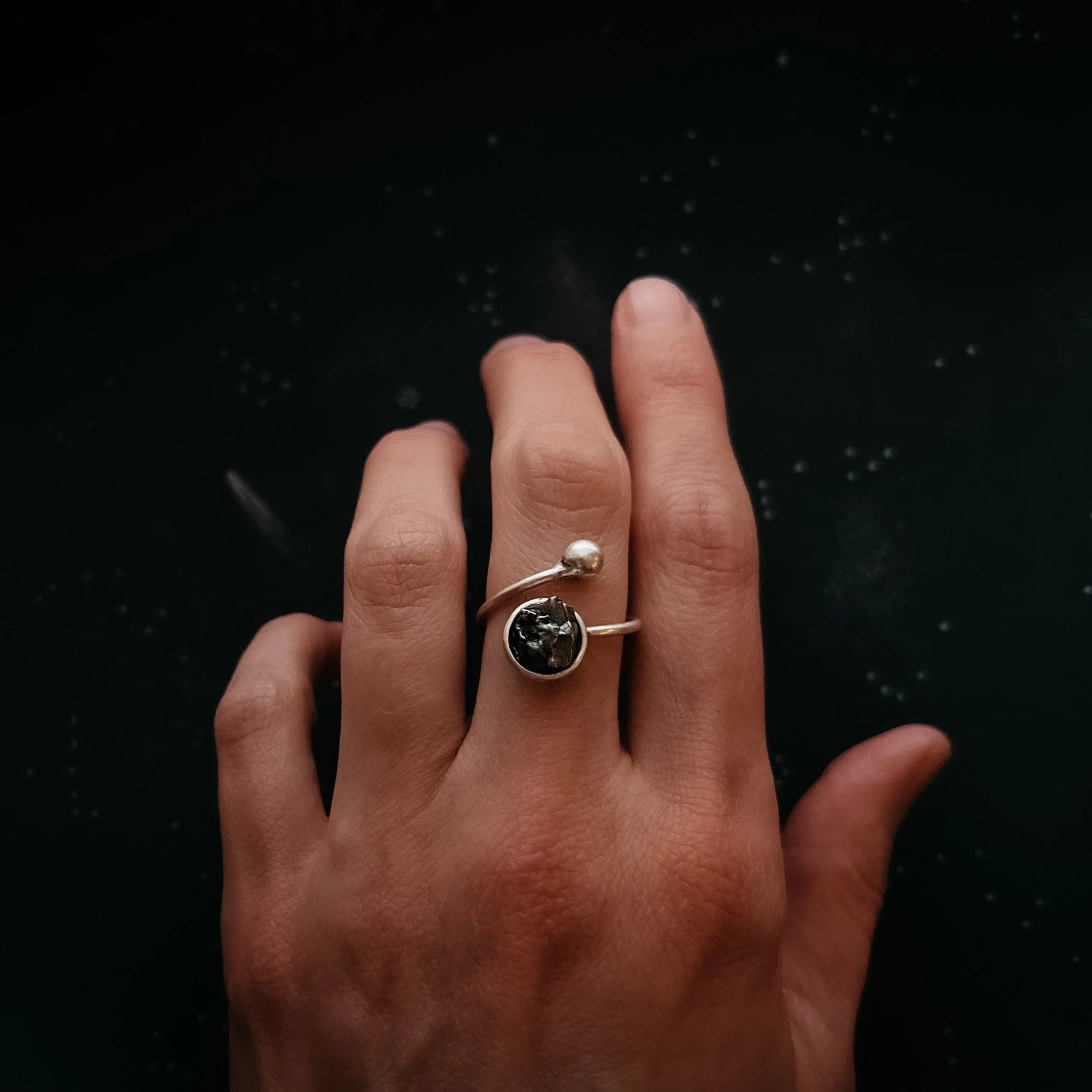 Hand wearing an artist-designed cosmic silver ring with black stone, Qu!rk Boutique jewelry