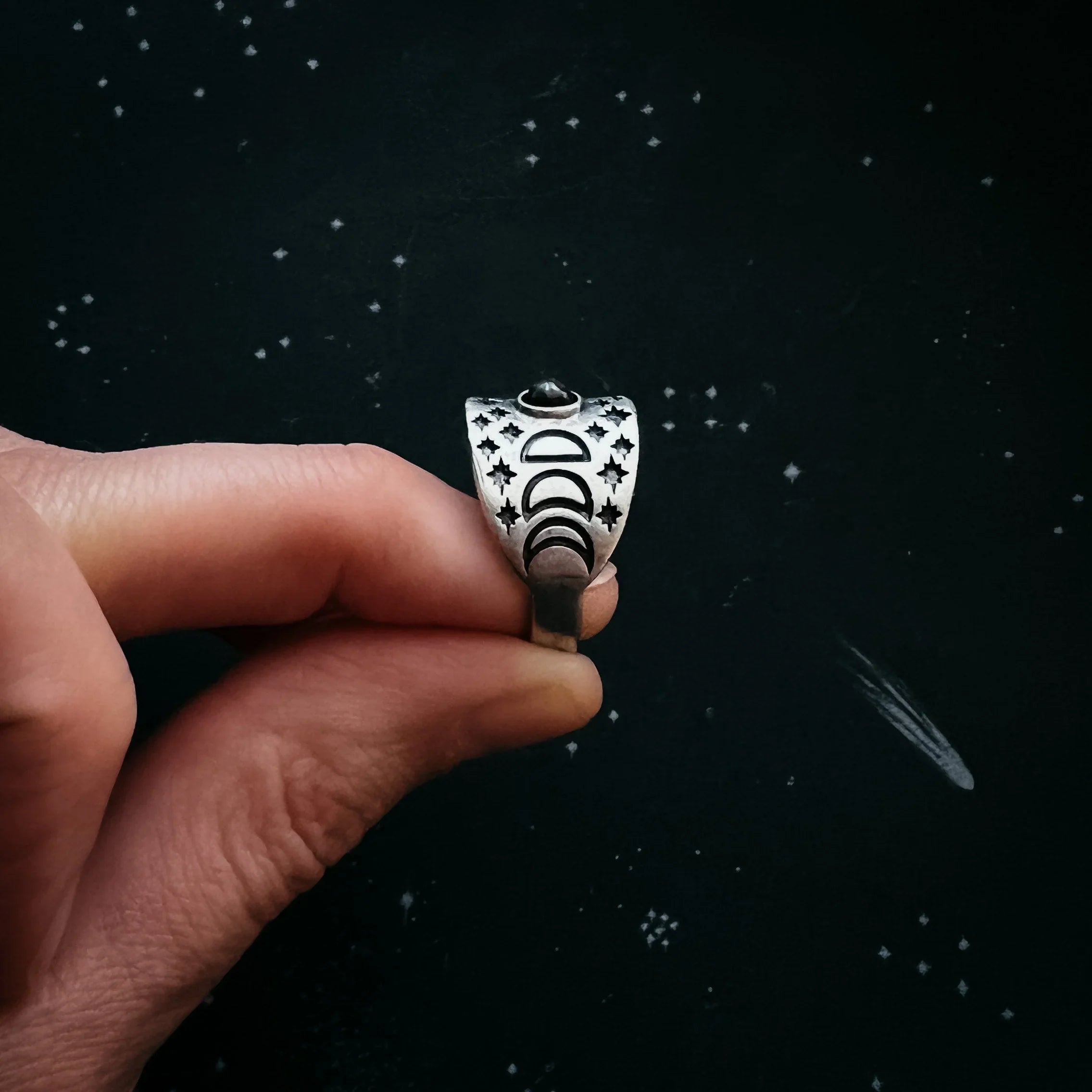 Hand holding celestial silver ring with moon phases and stars, cosmic jewelry at Qu!rk Boutique