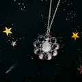 Silver moon phase necklace with celestial stars and shooting star on dark background